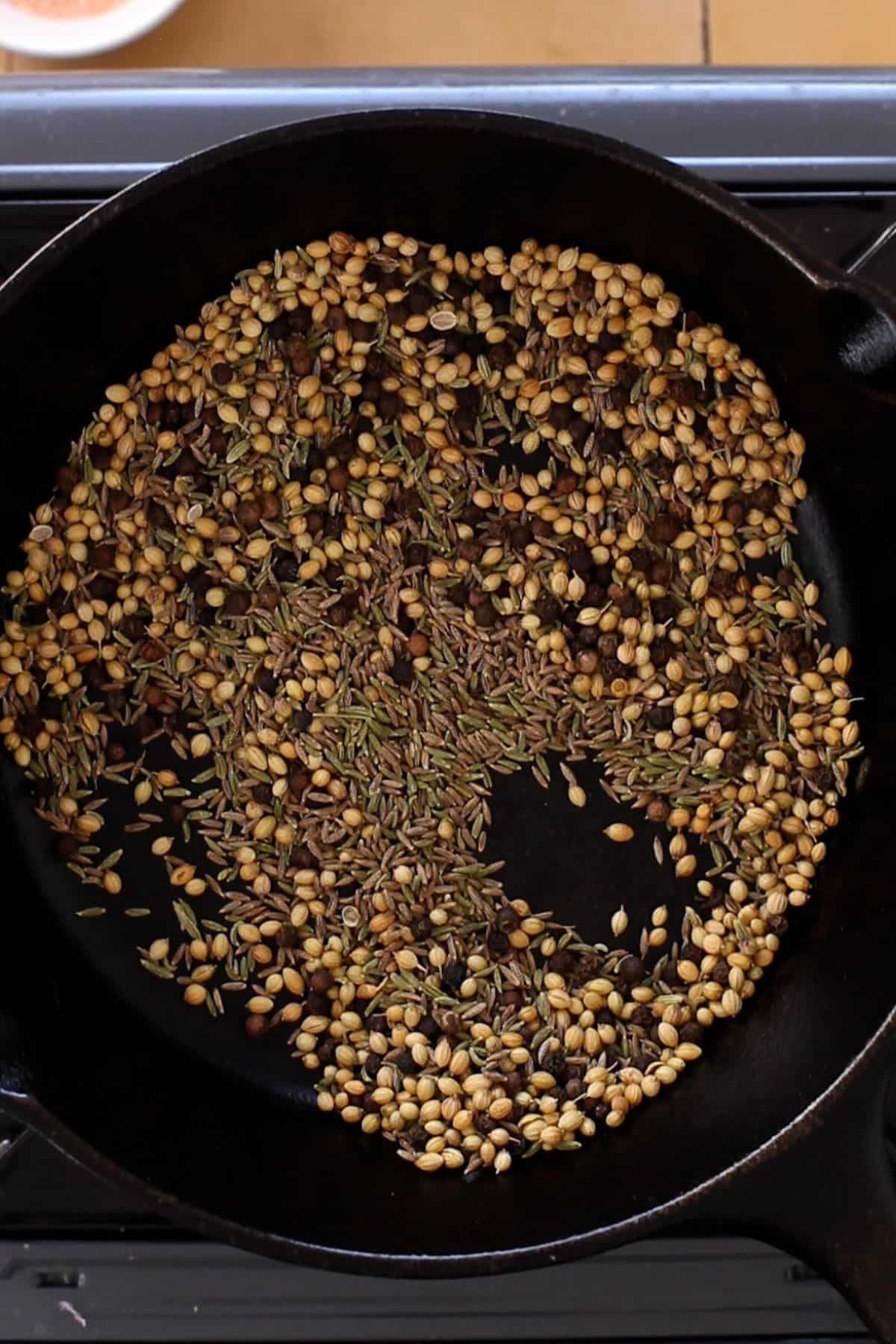 Whole spices in a cast iron skillet.