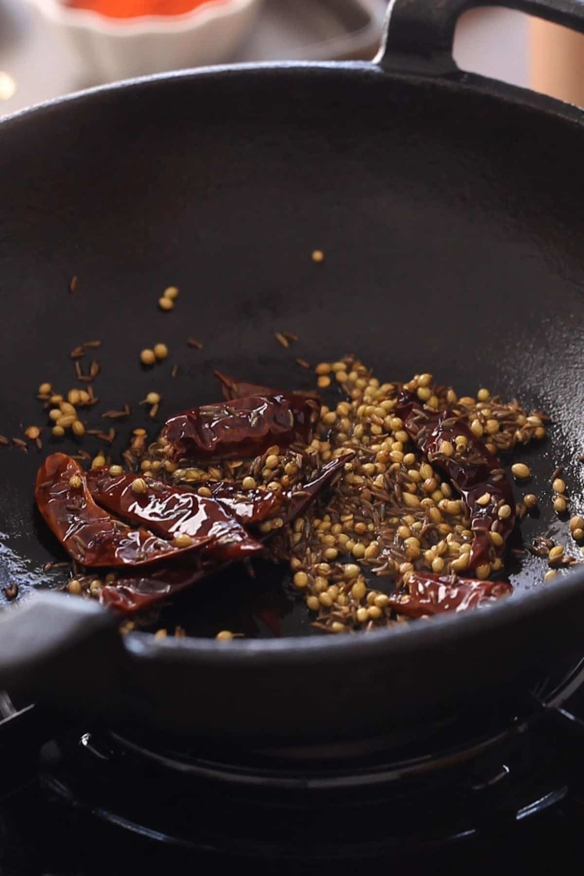 Roasting whole spices and dried chilies in oil.