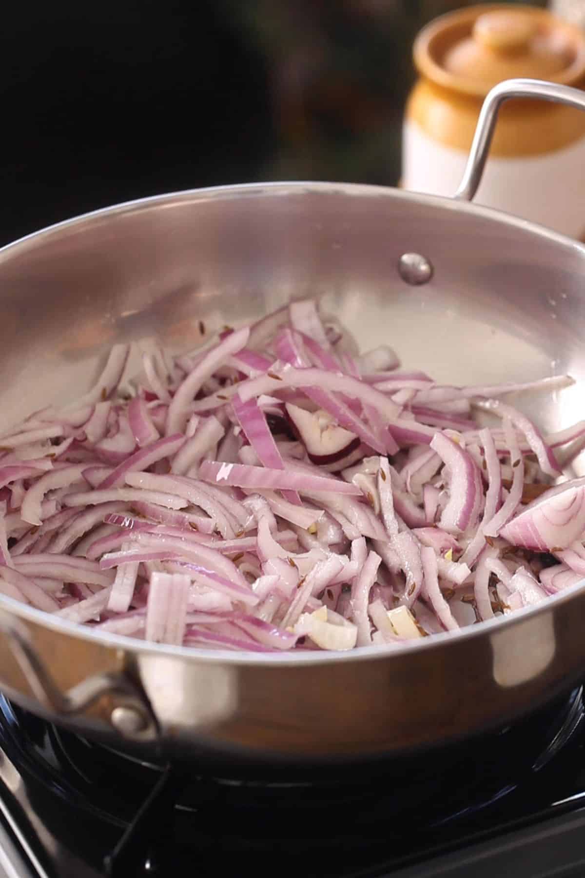 Sliced onions are added to hot oil.