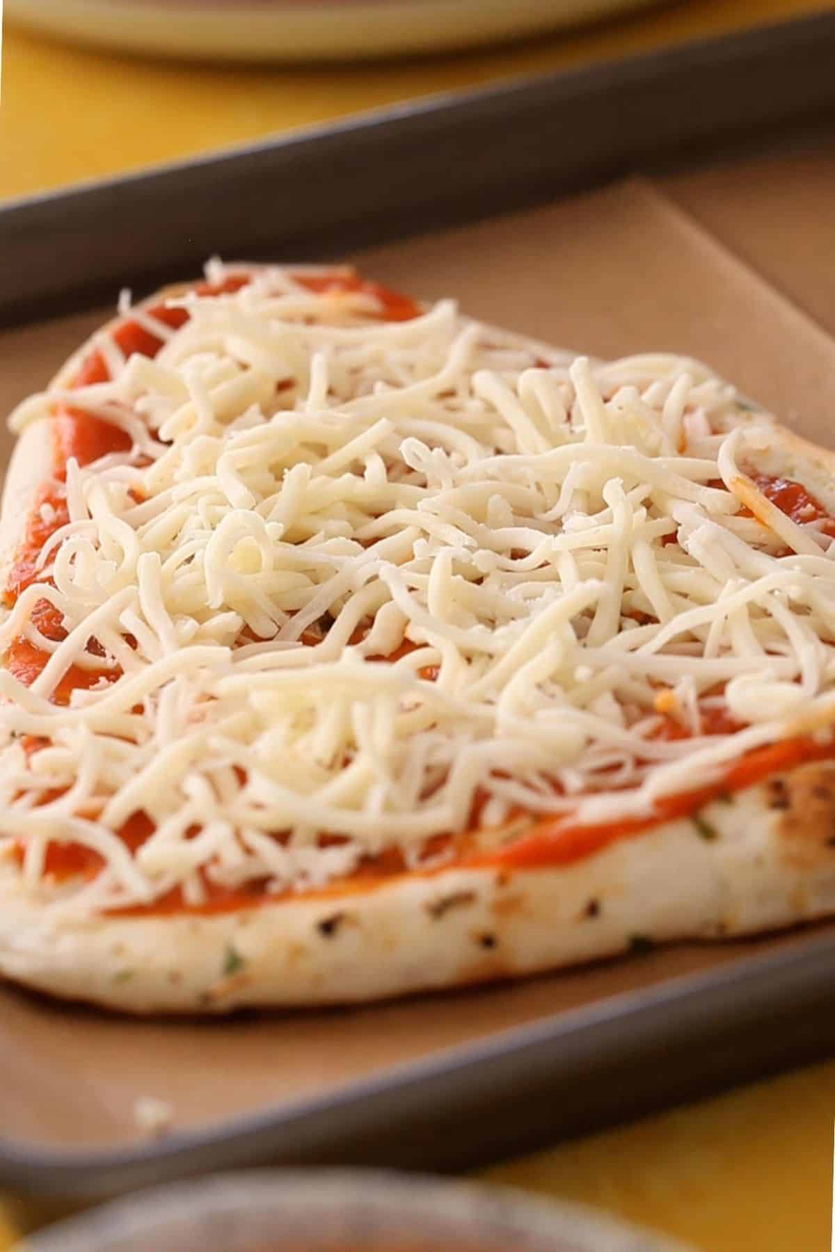 Shredded mozzarella cheese on garlic naan.