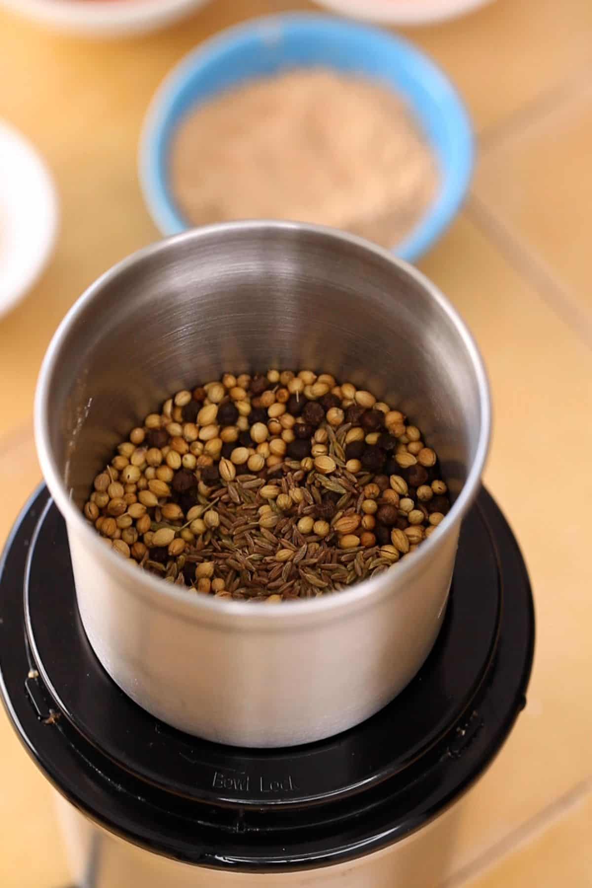Cooled roasted spices added in a spice grinder. 
