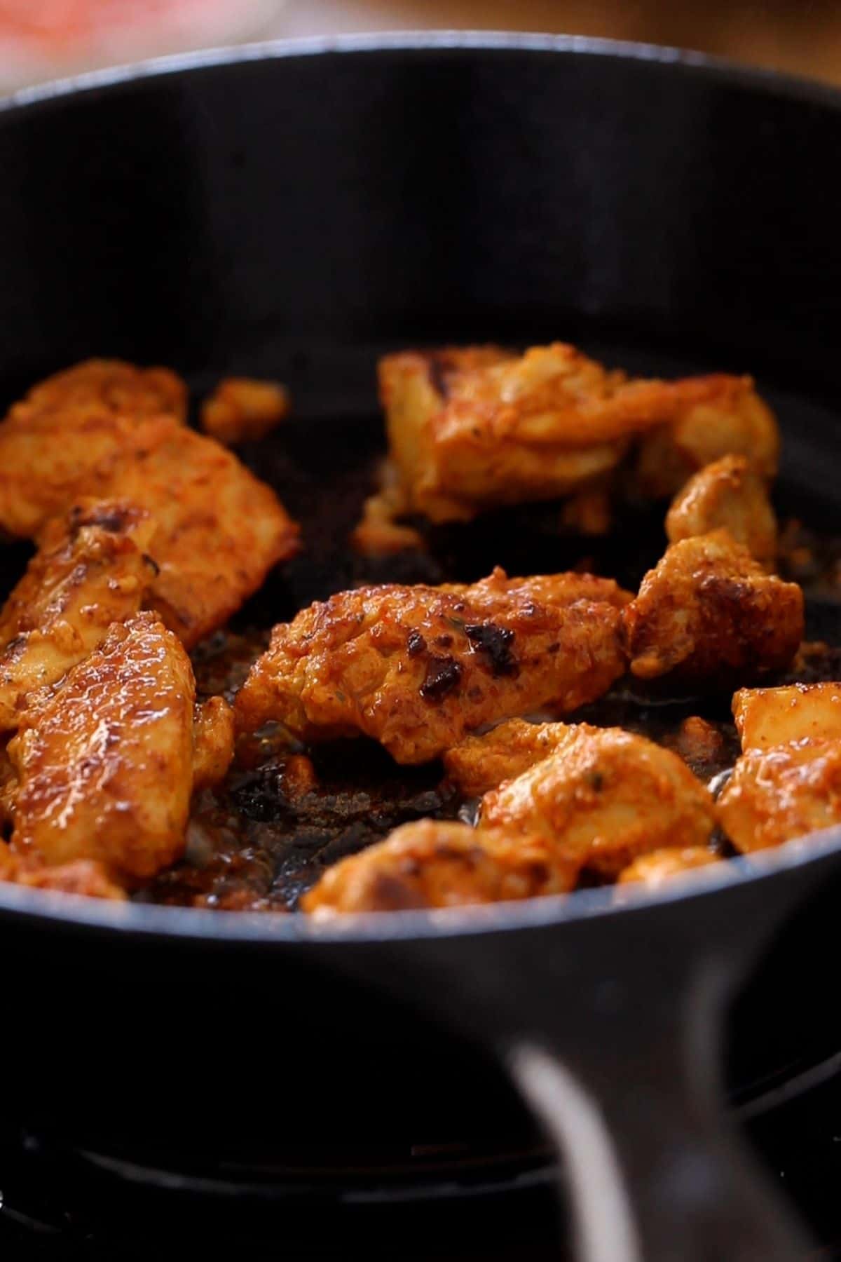 Cooked chicken tikka pan seared in a skillet.