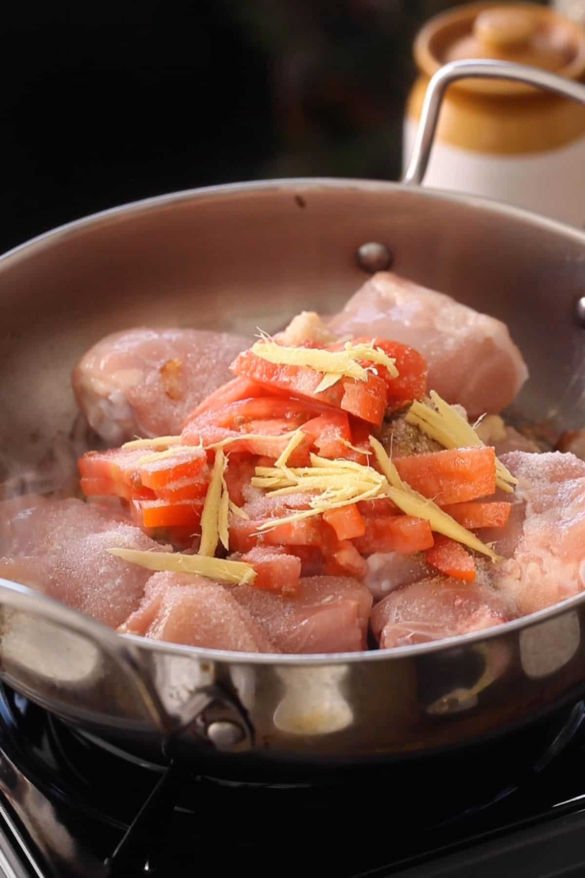 Chicken, tomatoes and spices are added to browned onions.