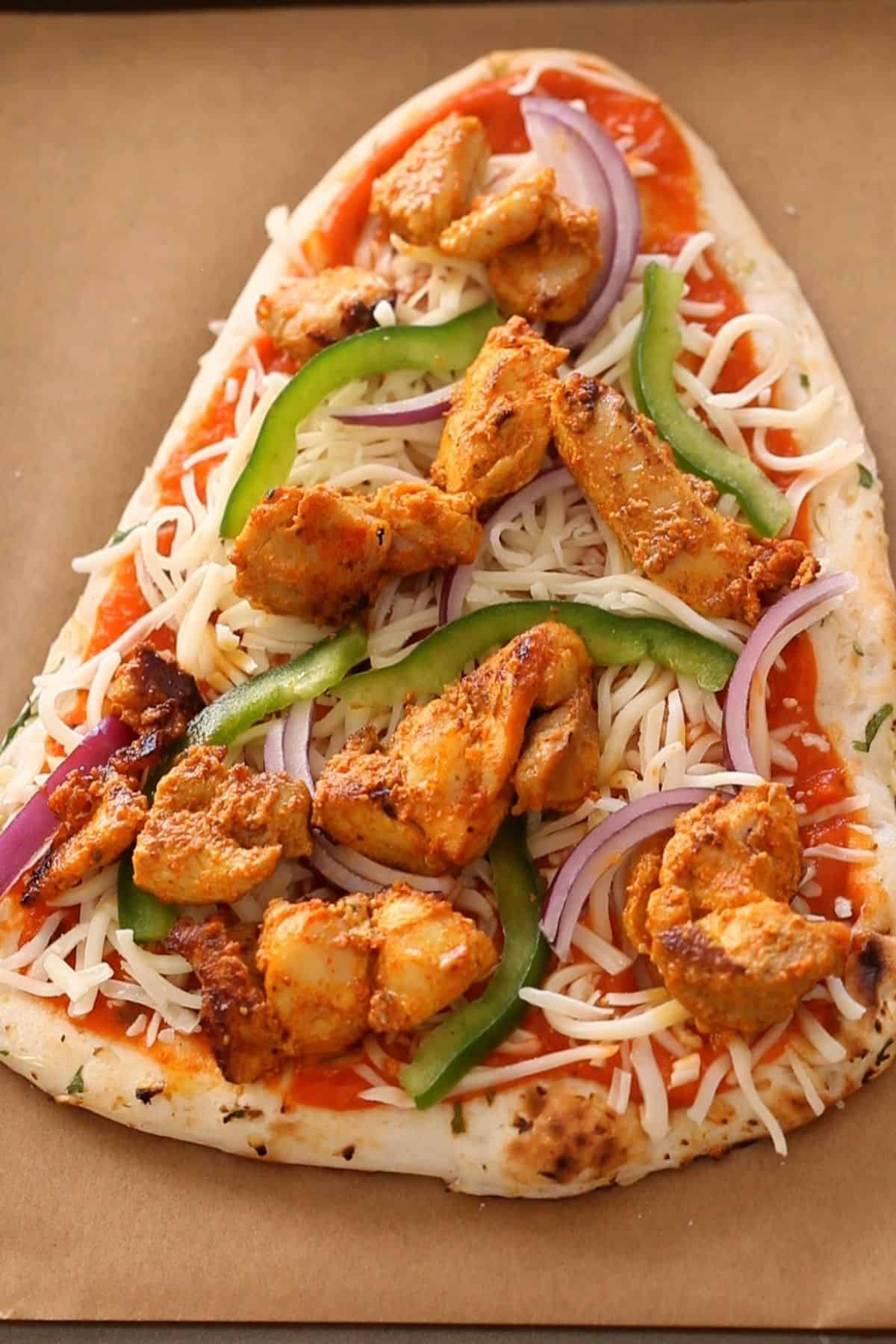 Chicken tikka, onion and bell peppper slices placed on naan.