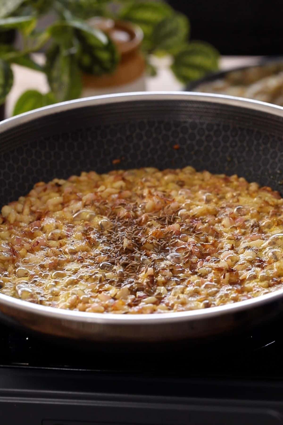 Adding cumin seeds to browned onions.