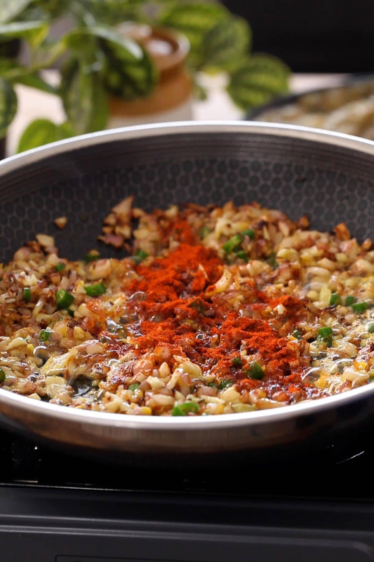 Red chili powder is added to the cooking pan.