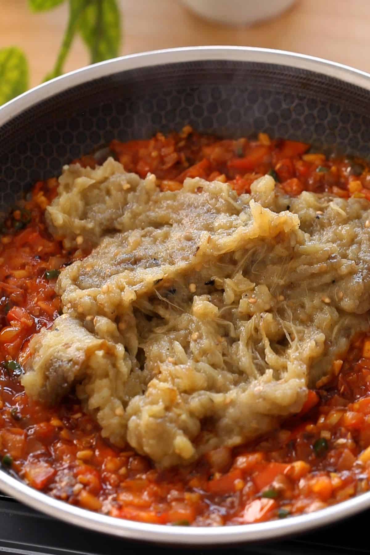 Eggplant mash is added to the onion -tomato masala.