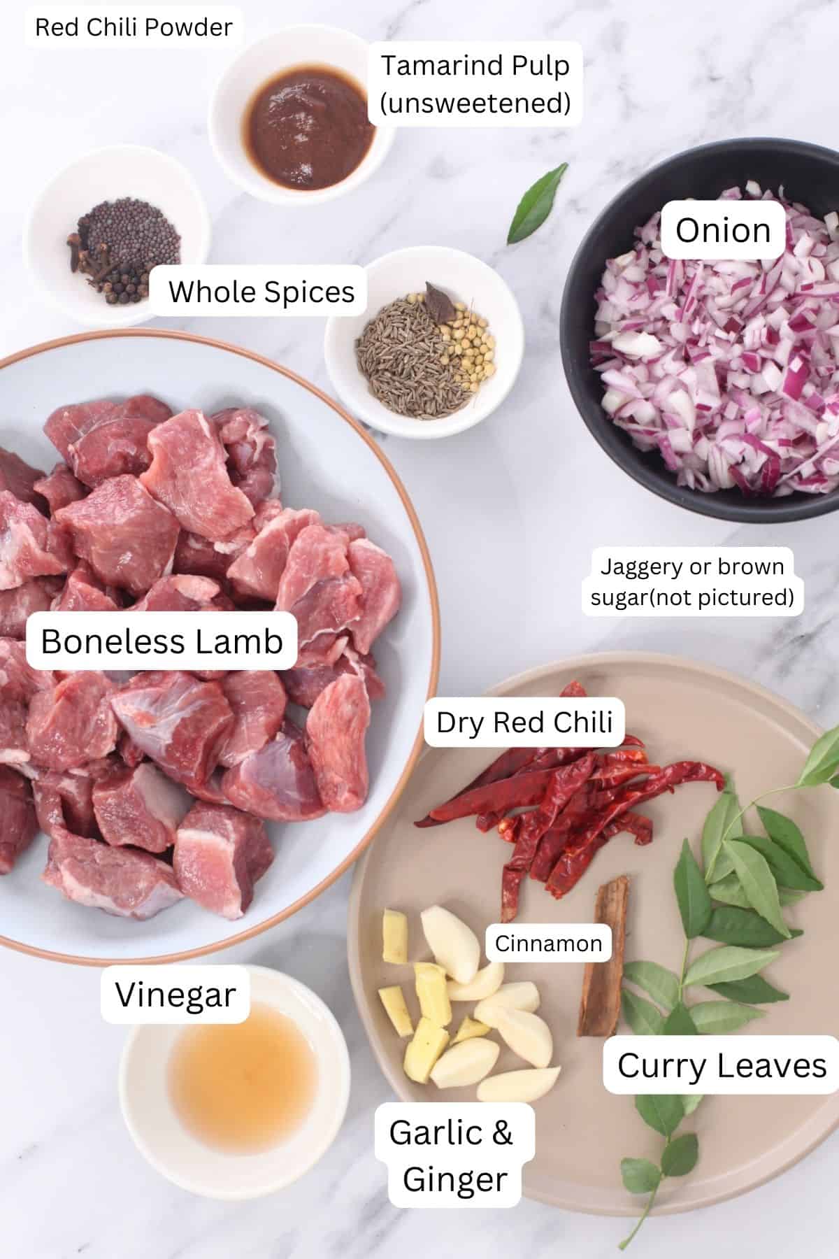 Ingredients Needed to make lamb vindaloo placed on a marble background.