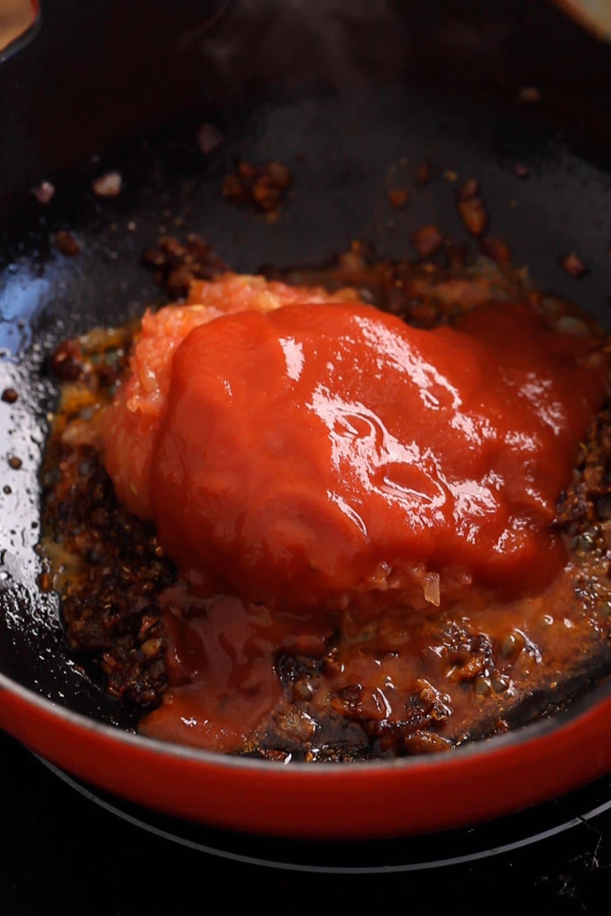 Tomatoes and tomato sauce are adeed to the kadai.