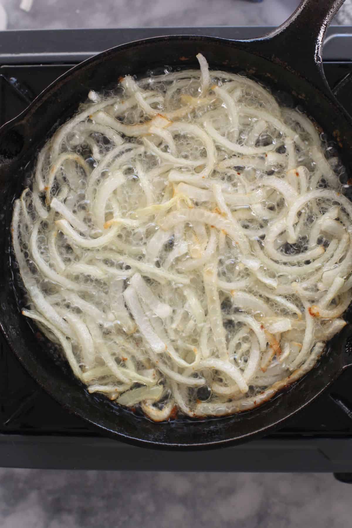 Deep frying onions in a cast iron skillet.