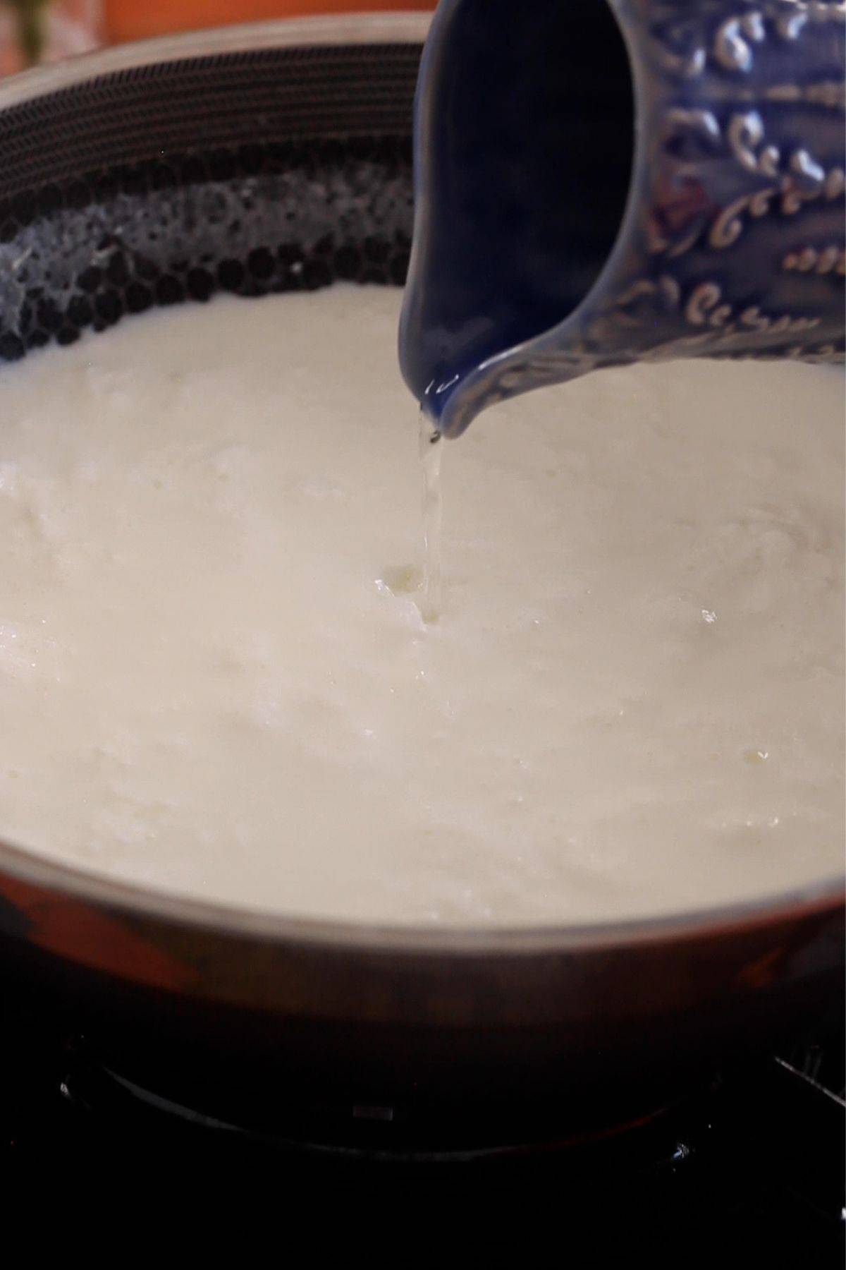 Adding vinegar and water mixture to curdle milk.