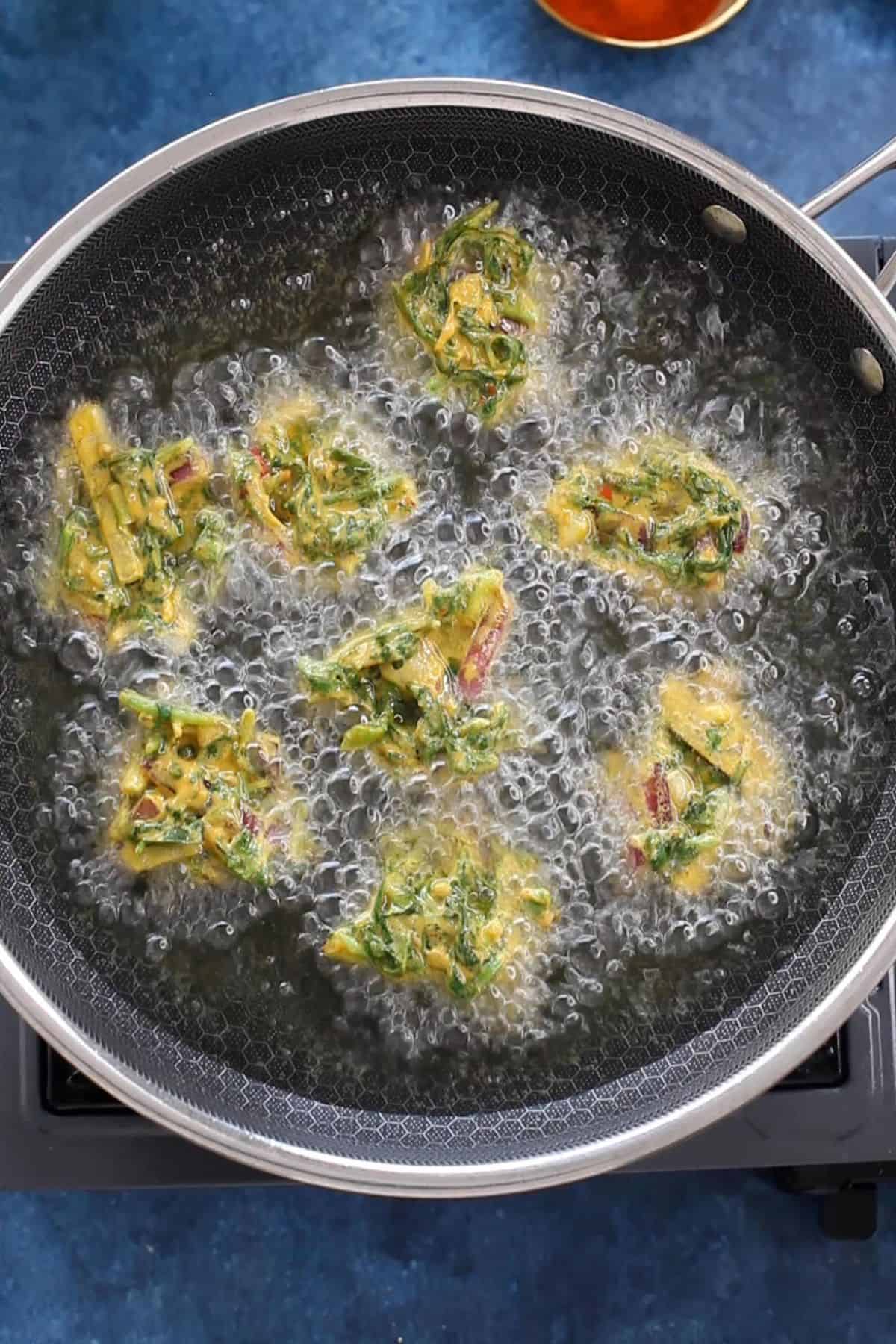 Palak pakoras are added to hot oil.