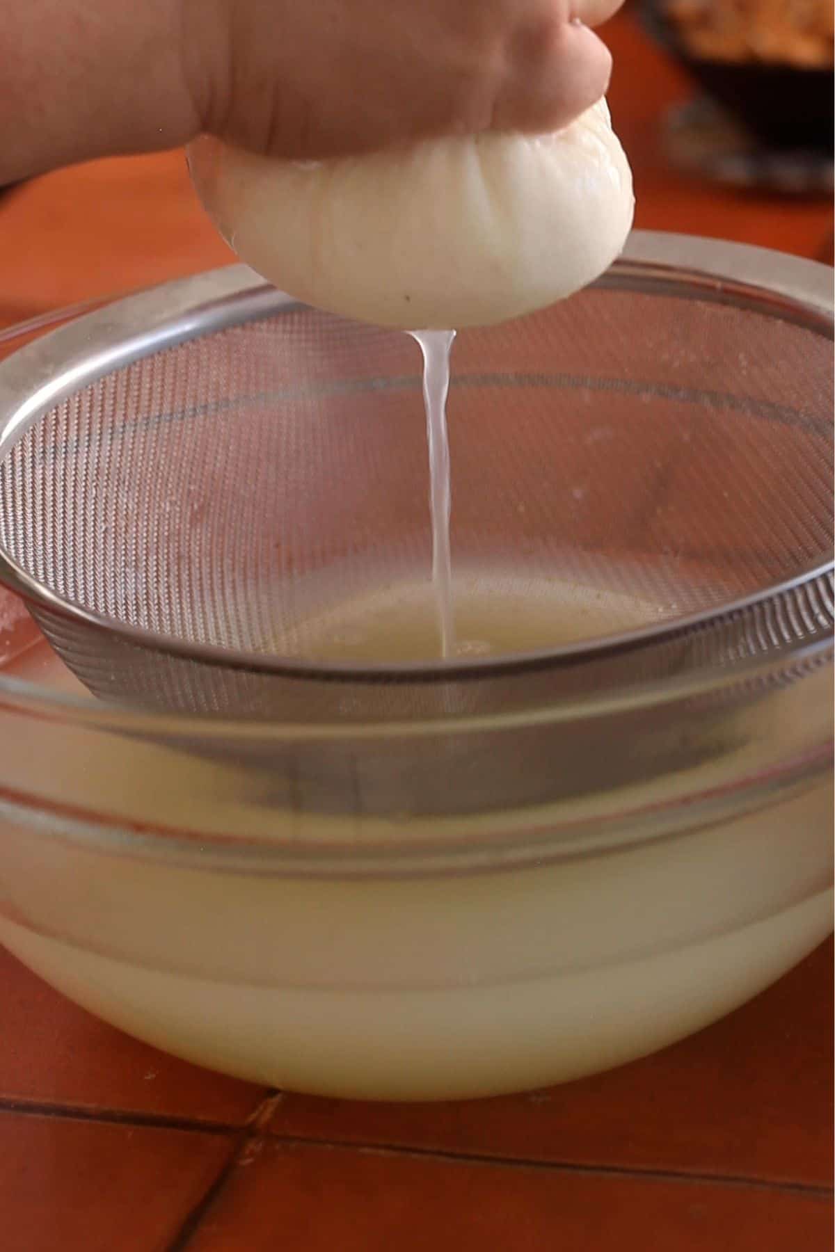 Squeezing the cheesecloth pouch to remove excess water.