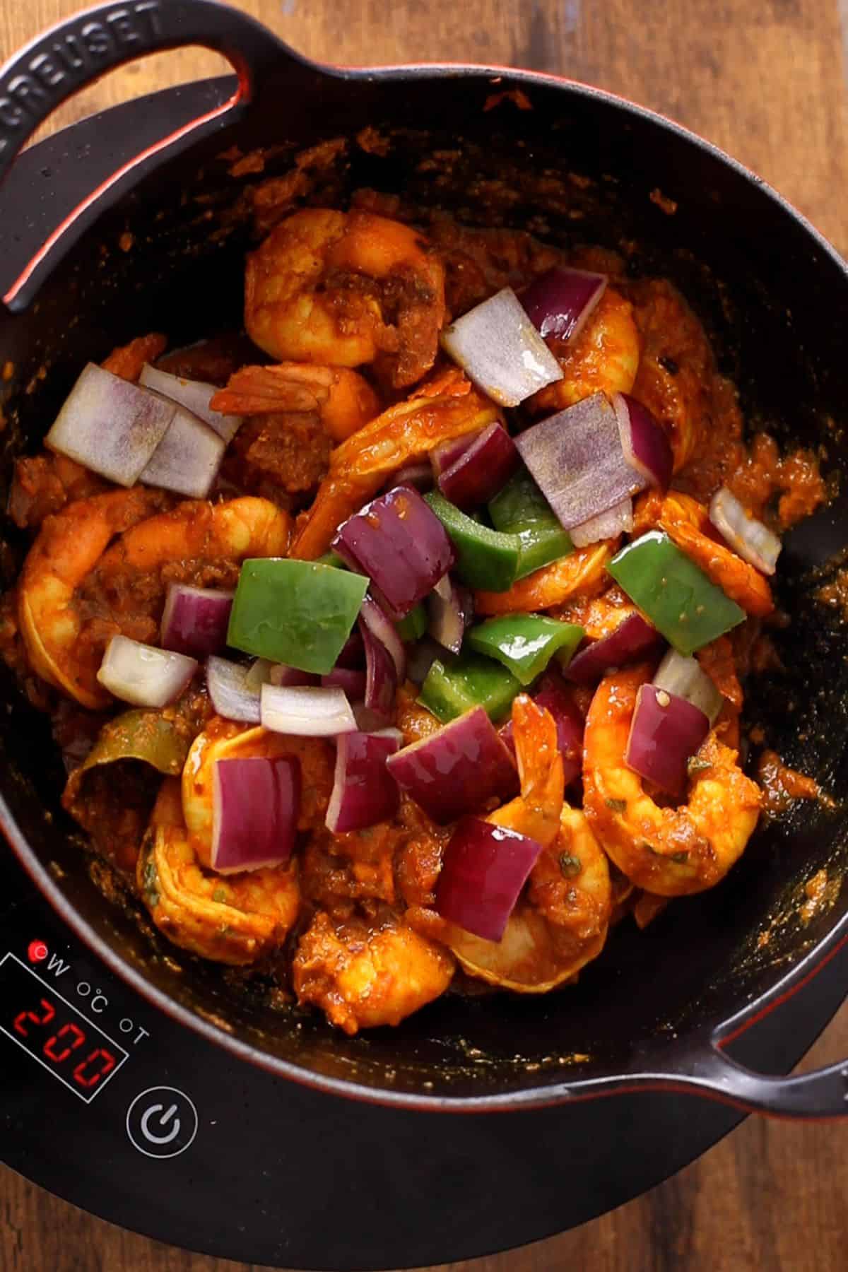 Adding bell pepper and onion to shrimp kadai.