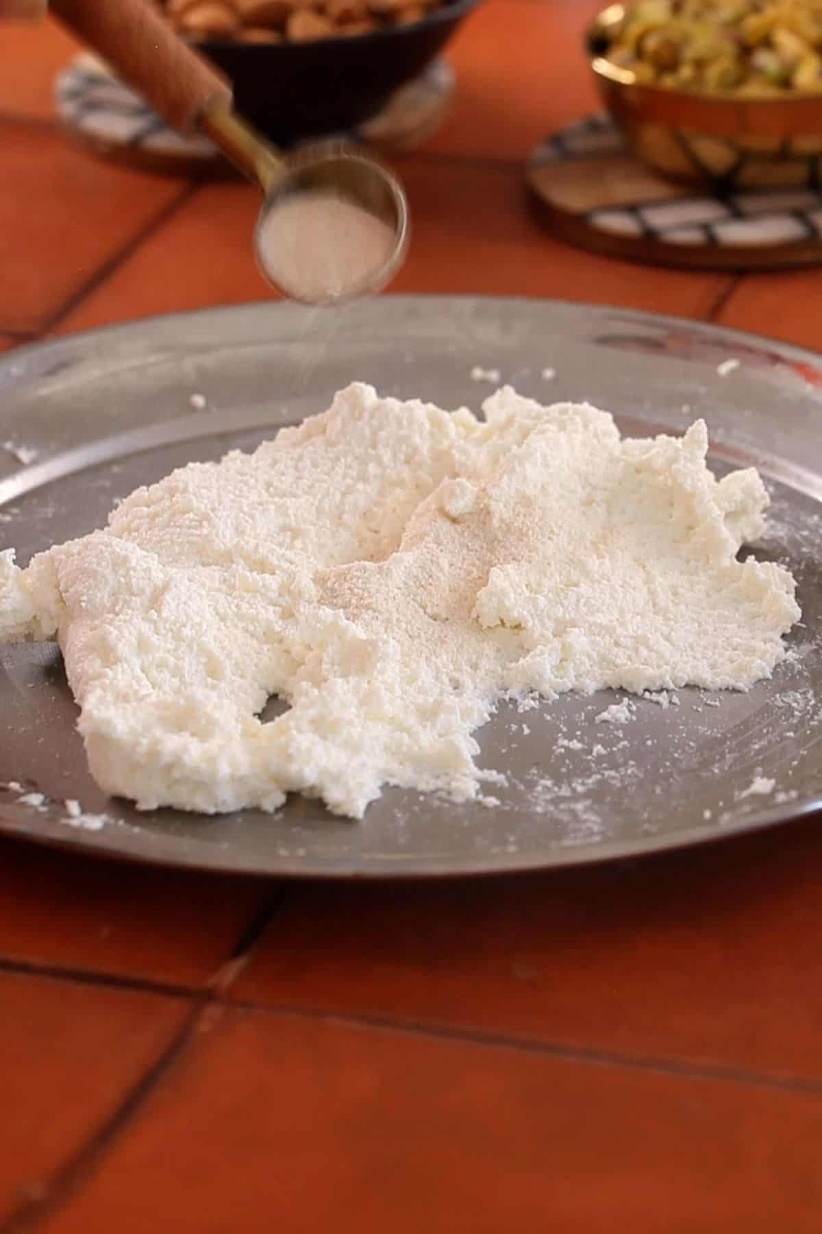 Kneaded chenna to which semolina is being added.