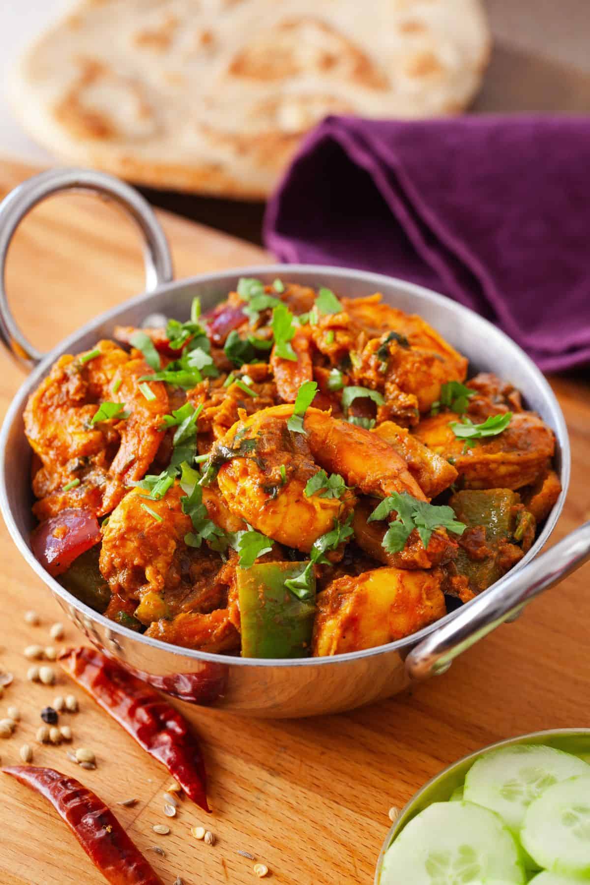 Kadai shrimp in a small indian wok with roti in background.