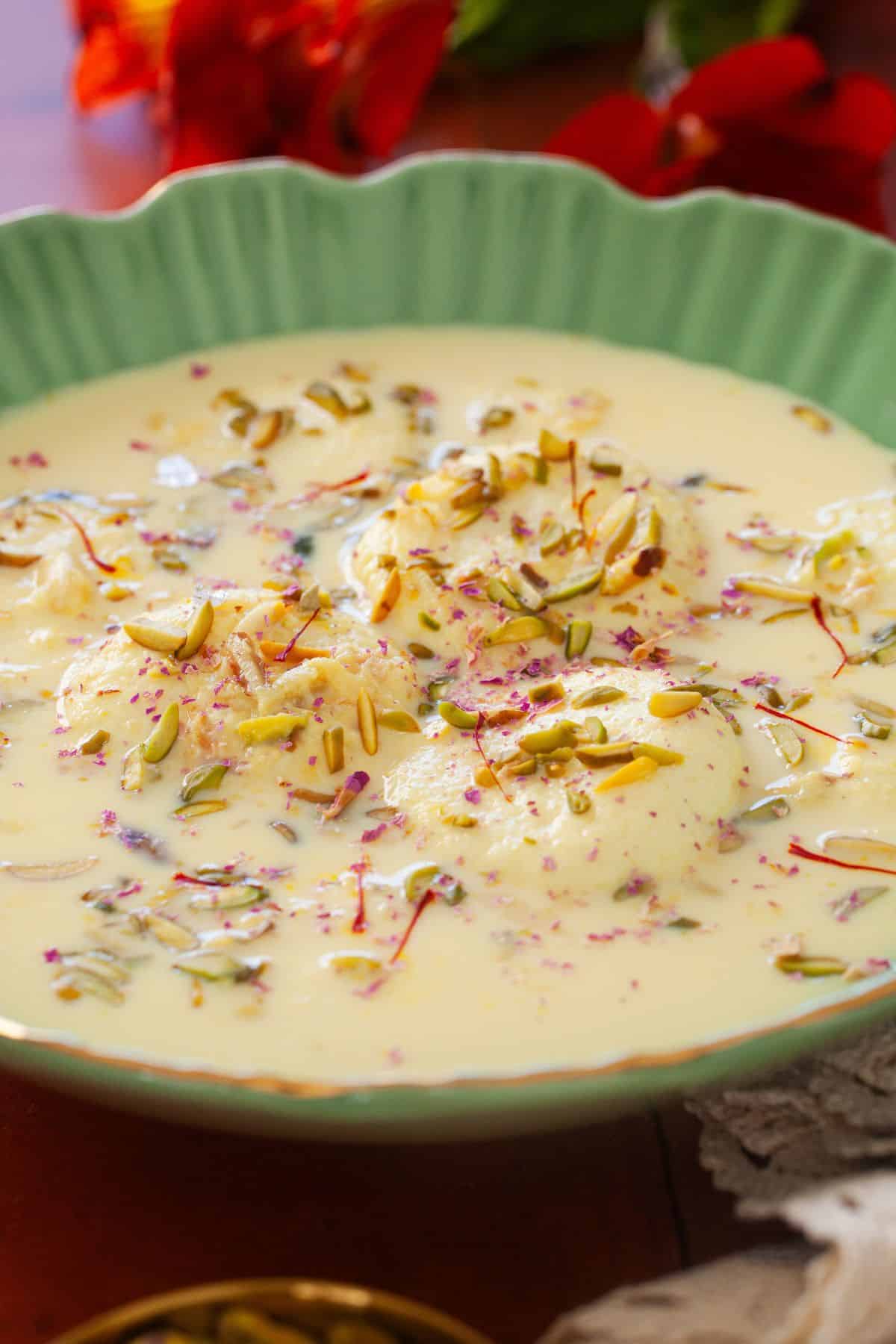 Close up image of rasmalai in a green bowl. 