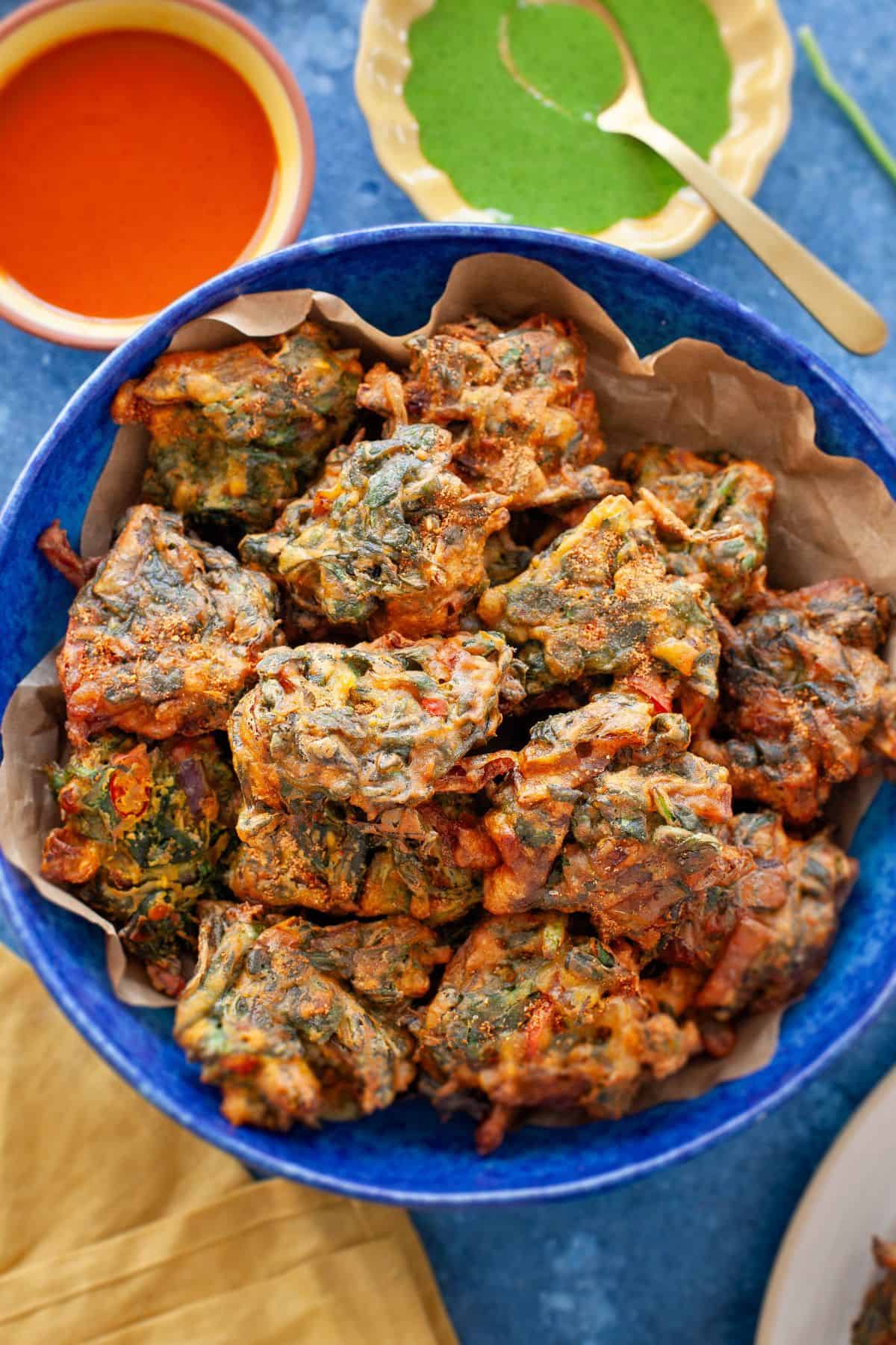 Close up image of palak pakora in a blue ceramic plate.