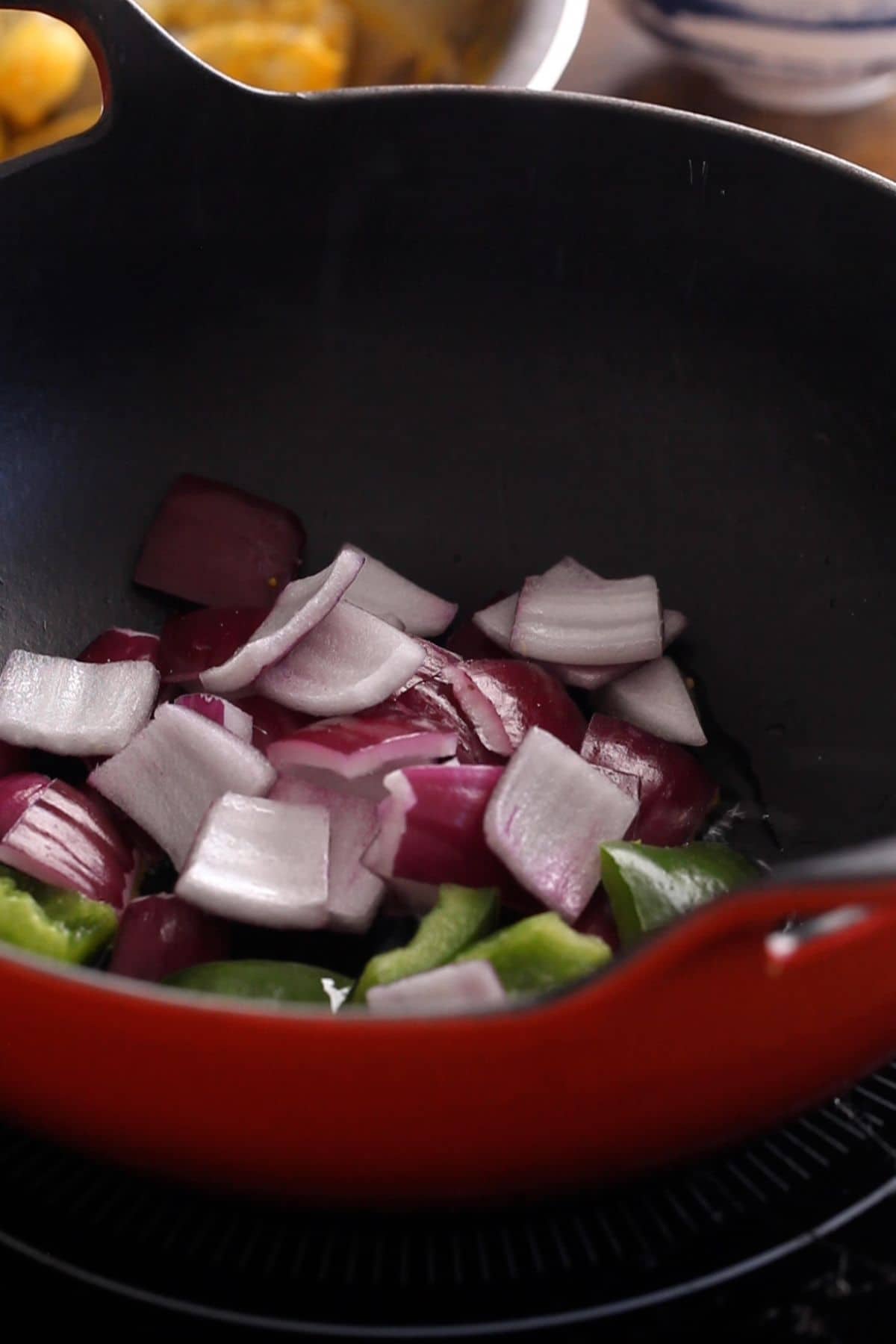 Cubed onion and bell pepper are added to oil.