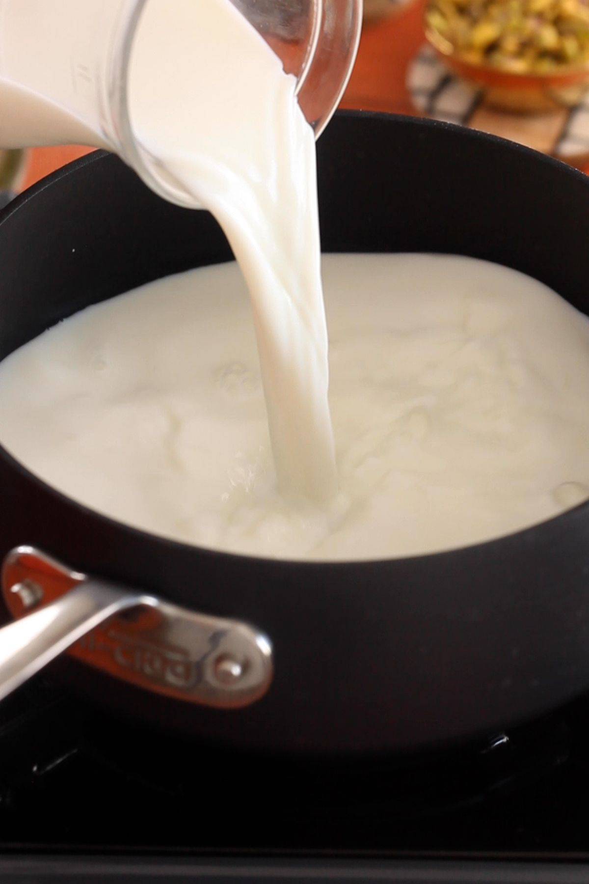 Milk is poured into a black pot.