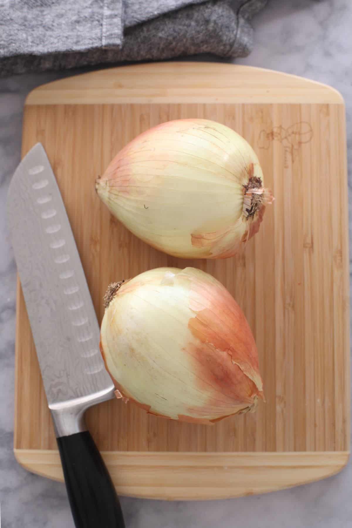 Large yellow onions placed on a cutting board.