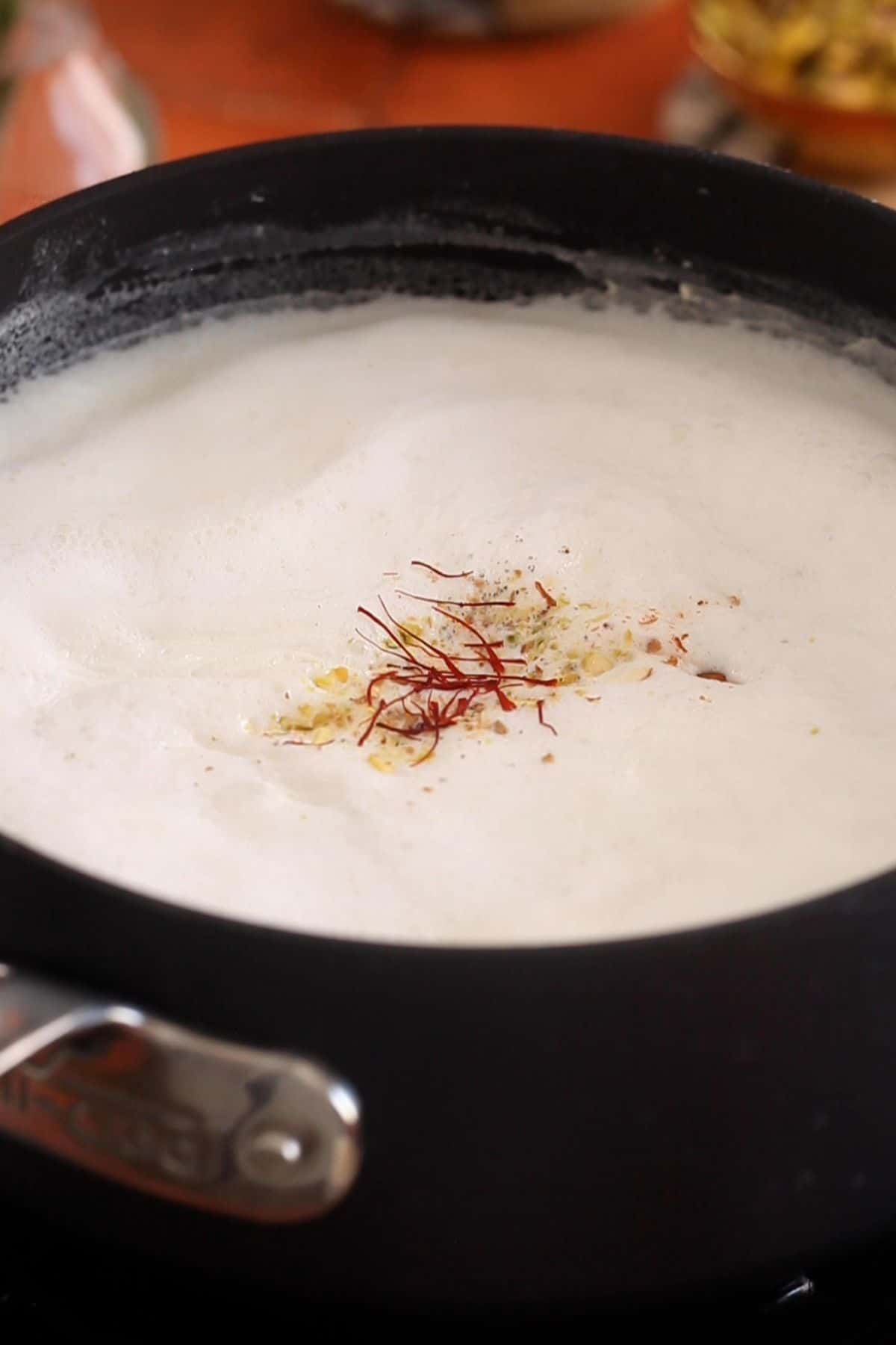 Chopped nuts, cardamom powder and saffron is added to boiled milk.