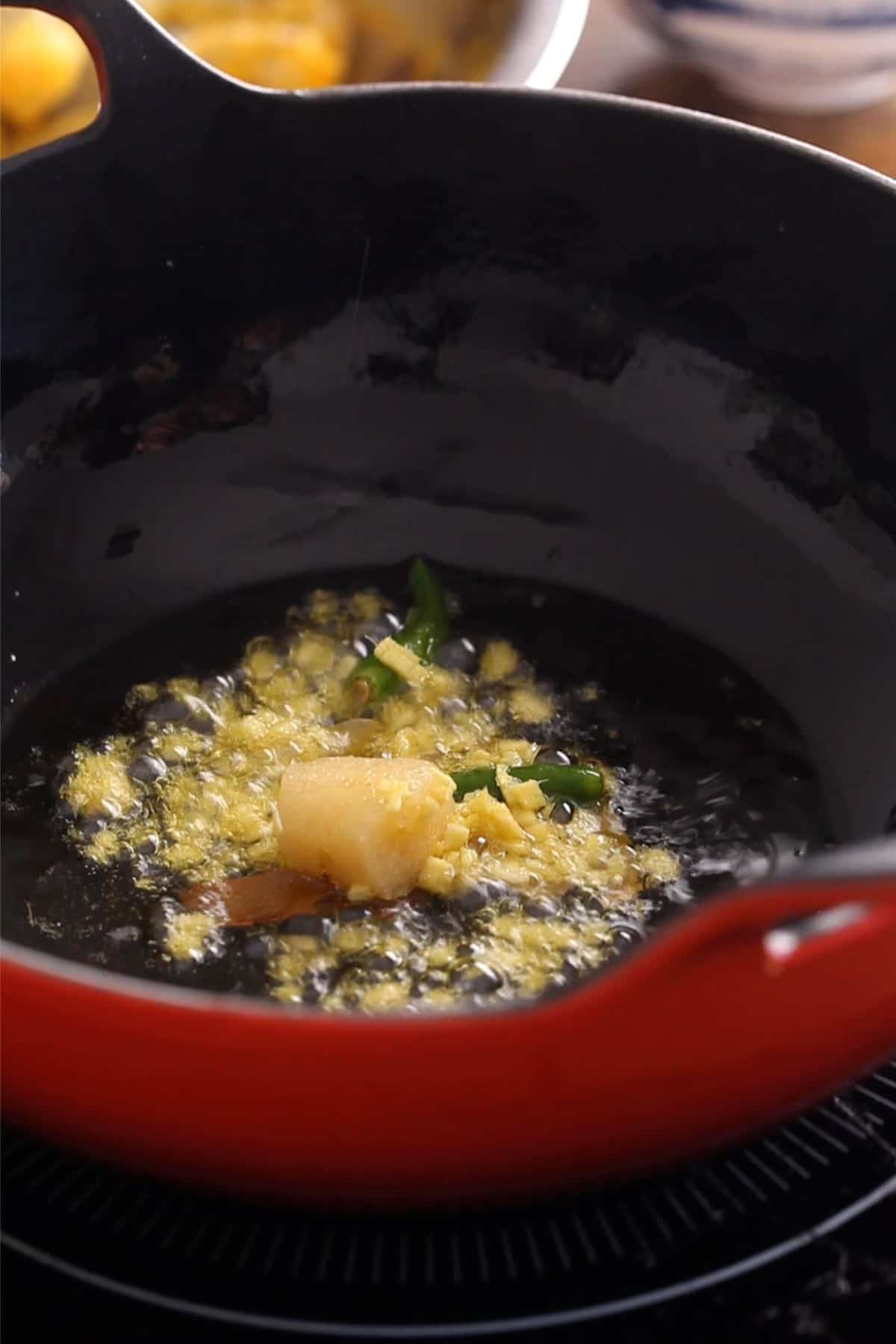 Garlic and whole spices are added to hot oil.