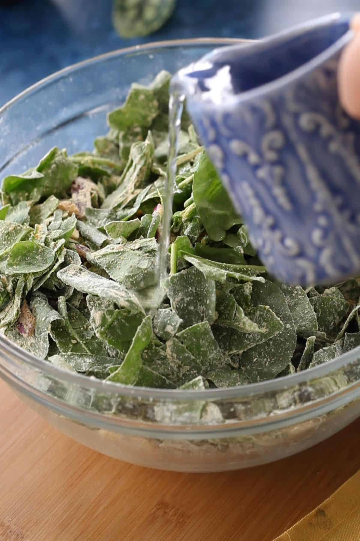 Water is gradually added to make pakora batter.