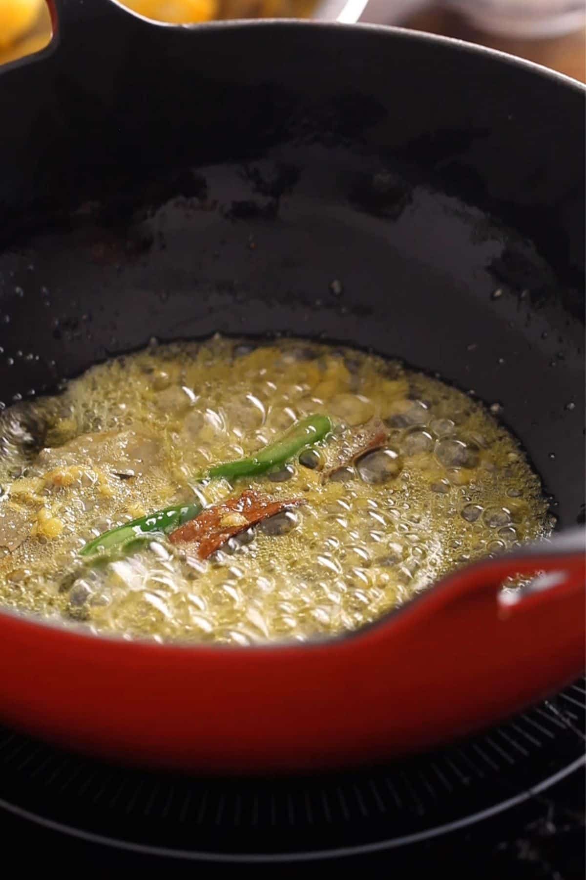 Spices and garlic are fried in oil to infuse flavors.