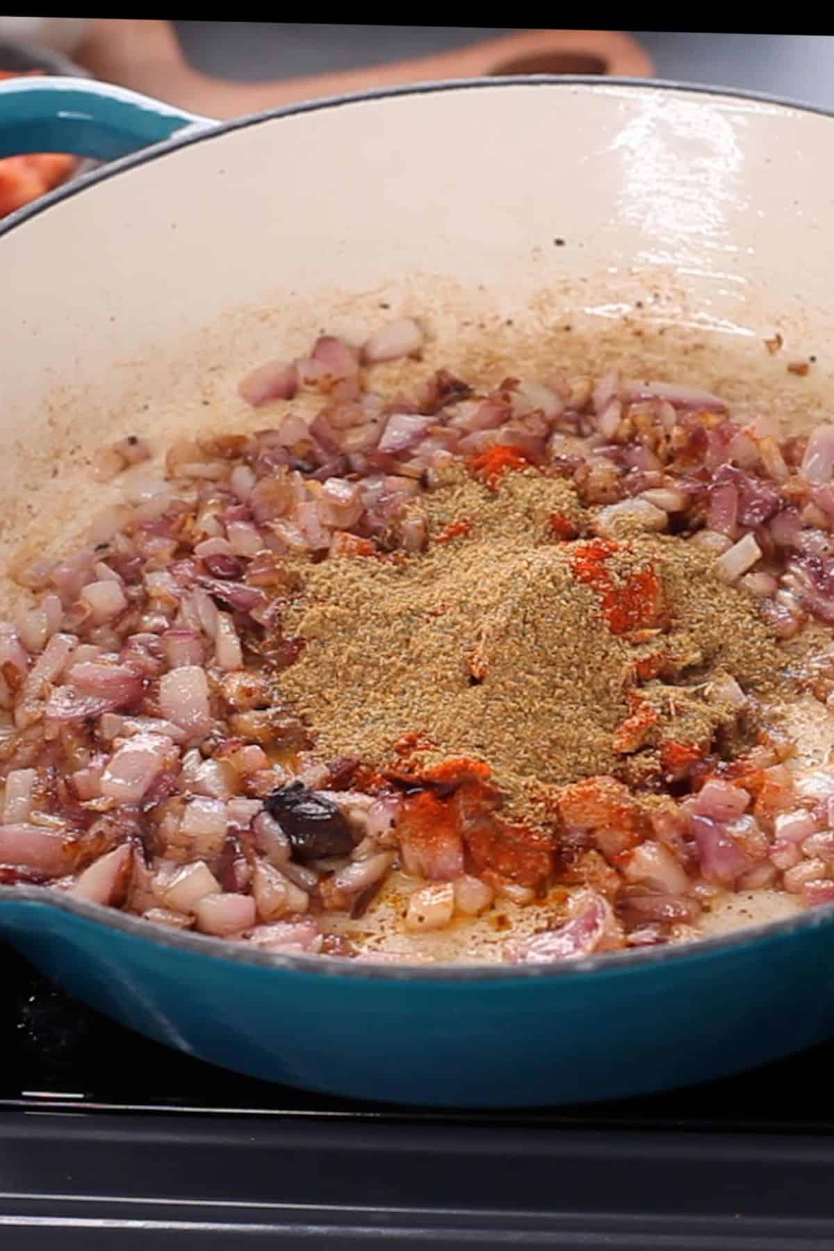 Spice powders are added to golden brown onions.