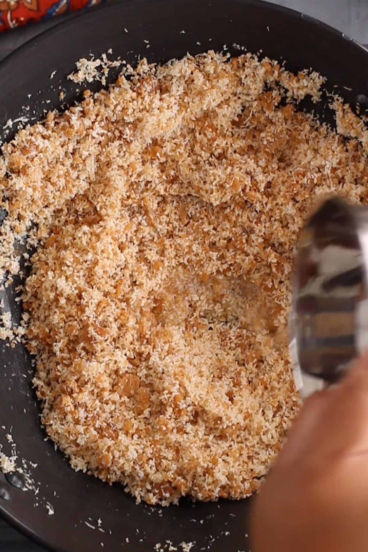 Water is gradually added to the coconut and jaggery mixture.