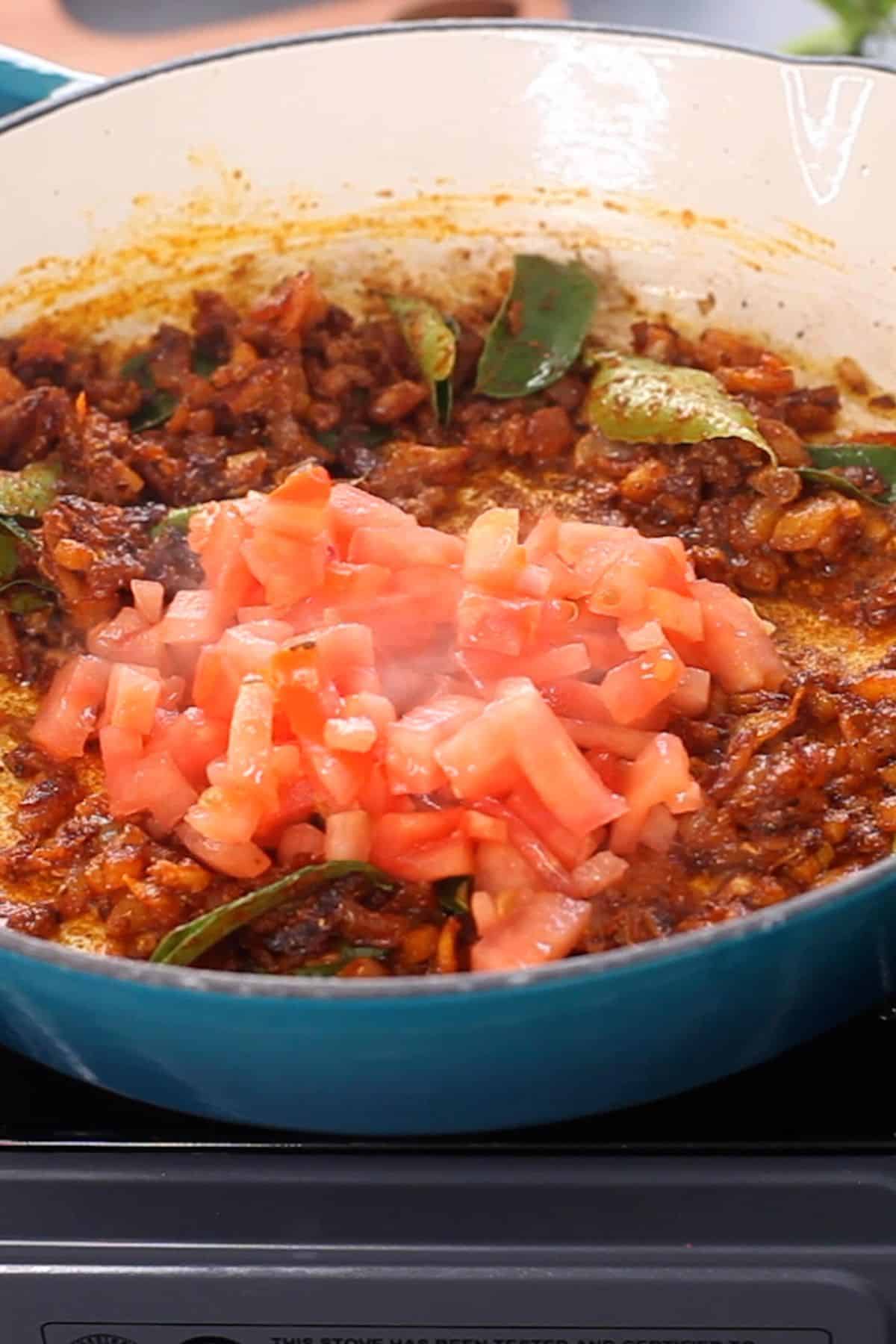 Chopped tomatoes are added to onion masala.