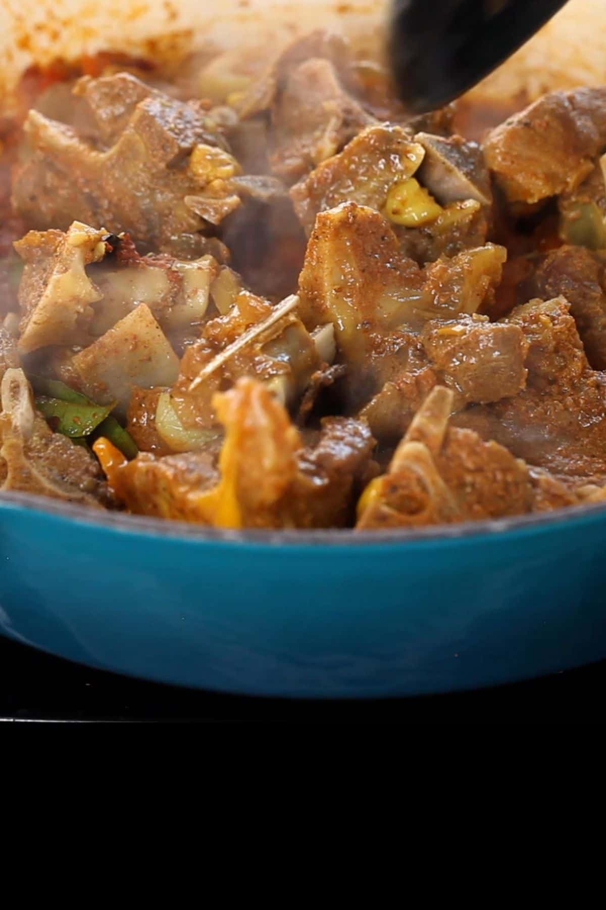 Cooked meat pieces are added to the masala and stir frying beings.
