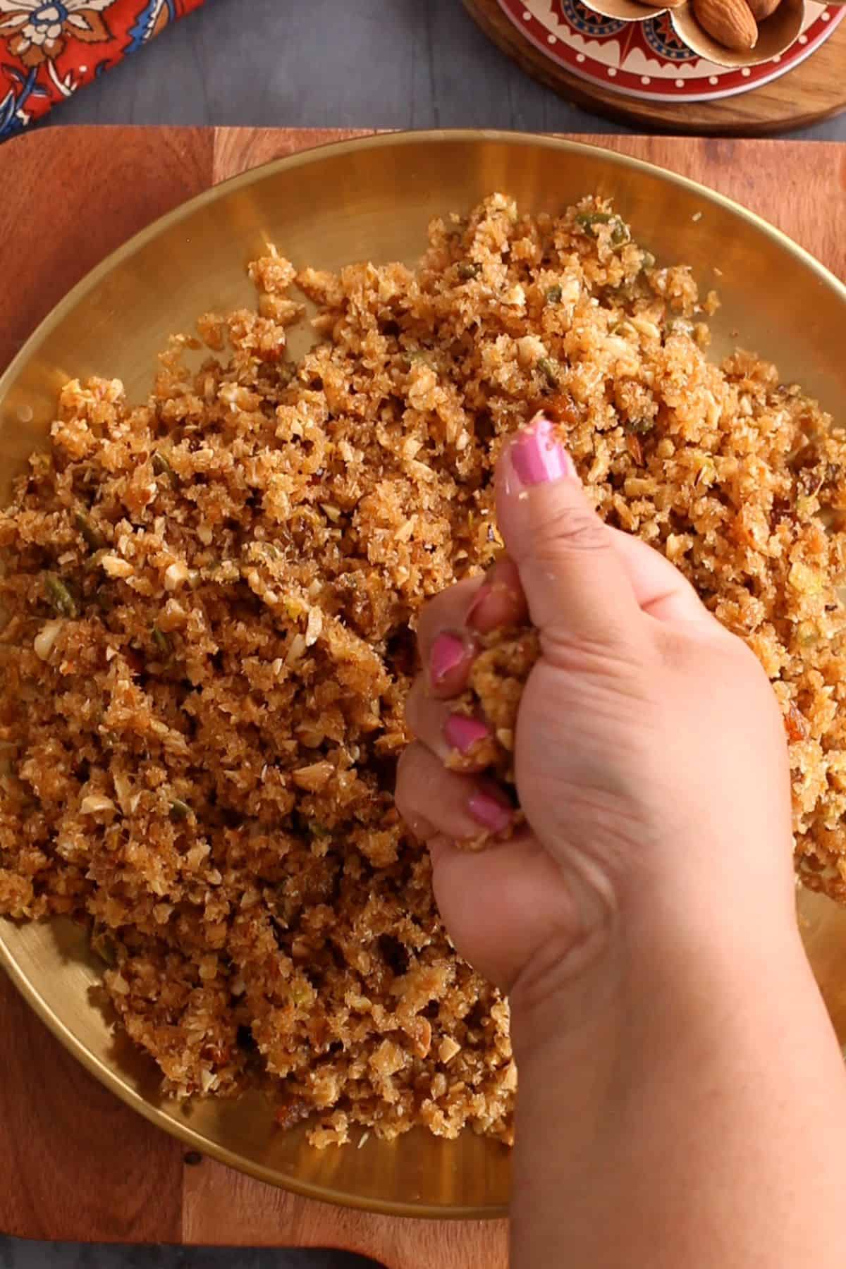 Shaping ladoos by pressing the coconut mixture into small balls.