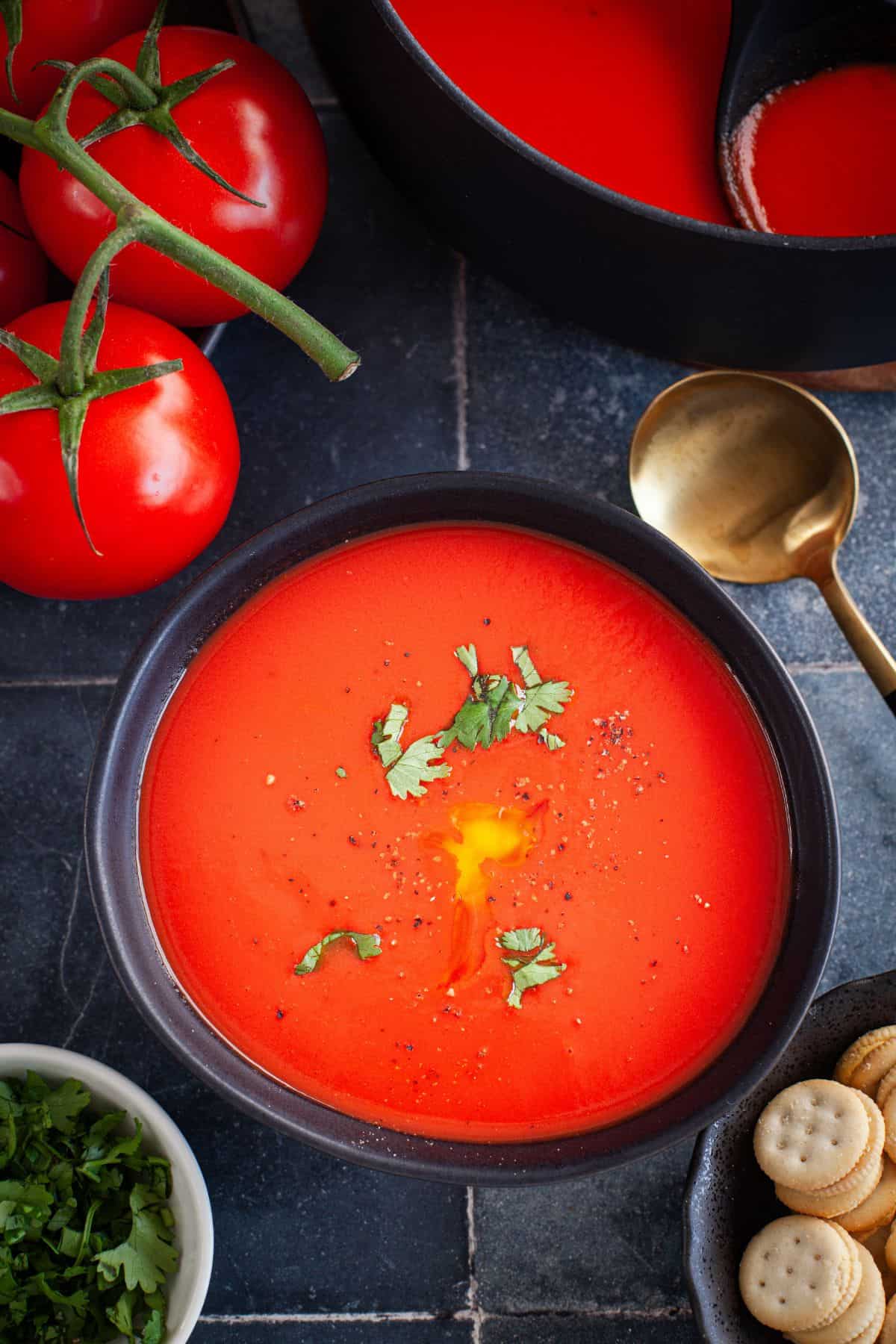 Tomato Soup served in a black bowl and garnished with black pepper.