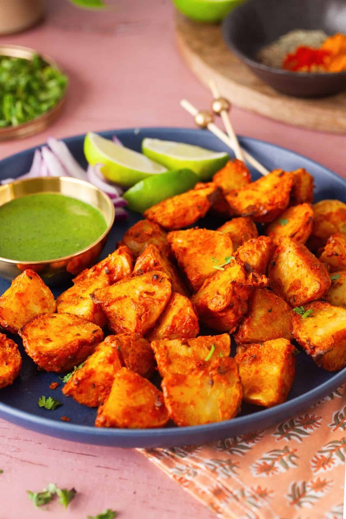 Side view of achari aloo tikka in a blue plate.