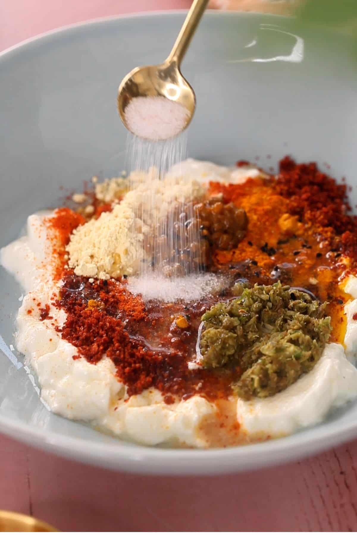 Adding salt to the achari marinade.