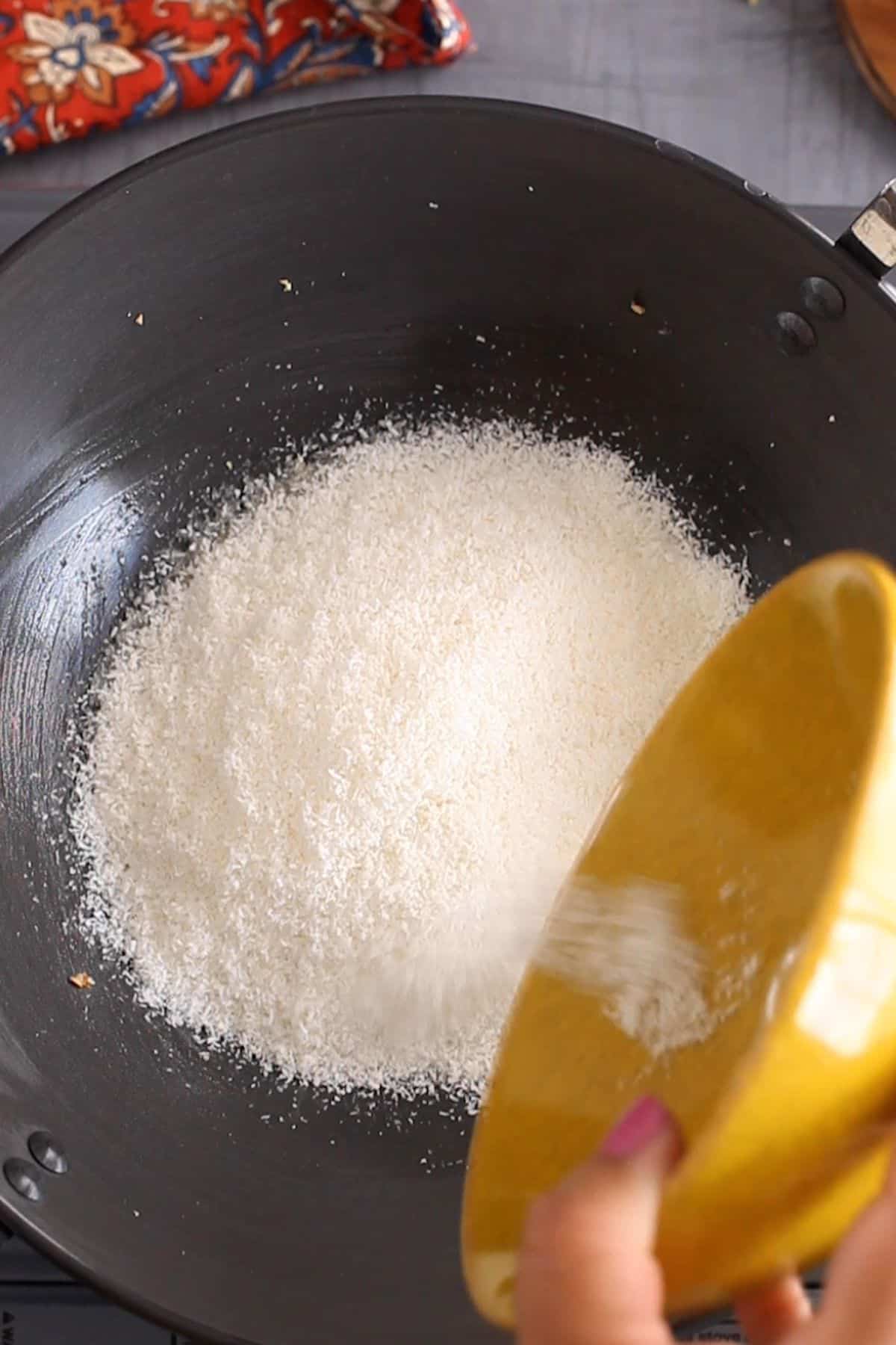 Adding dried dessicated coconut to the ghee.