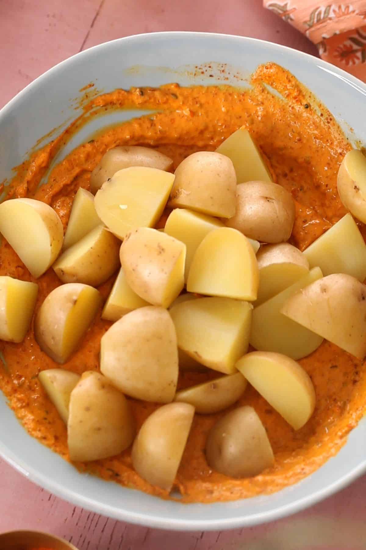 Par boiled potatoes are added to the achari marinade.