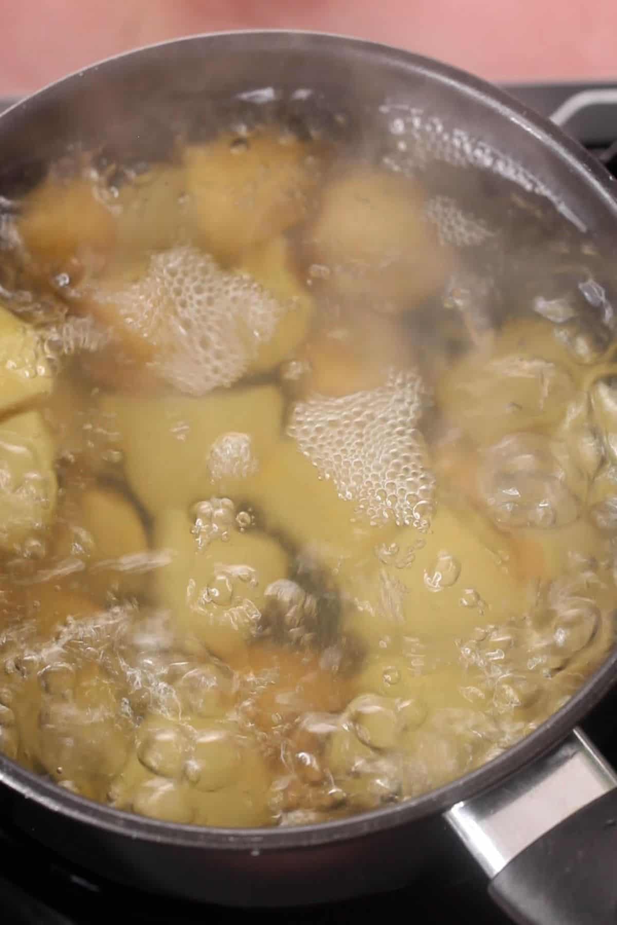 Boiling potatoes in a black cooking pot.