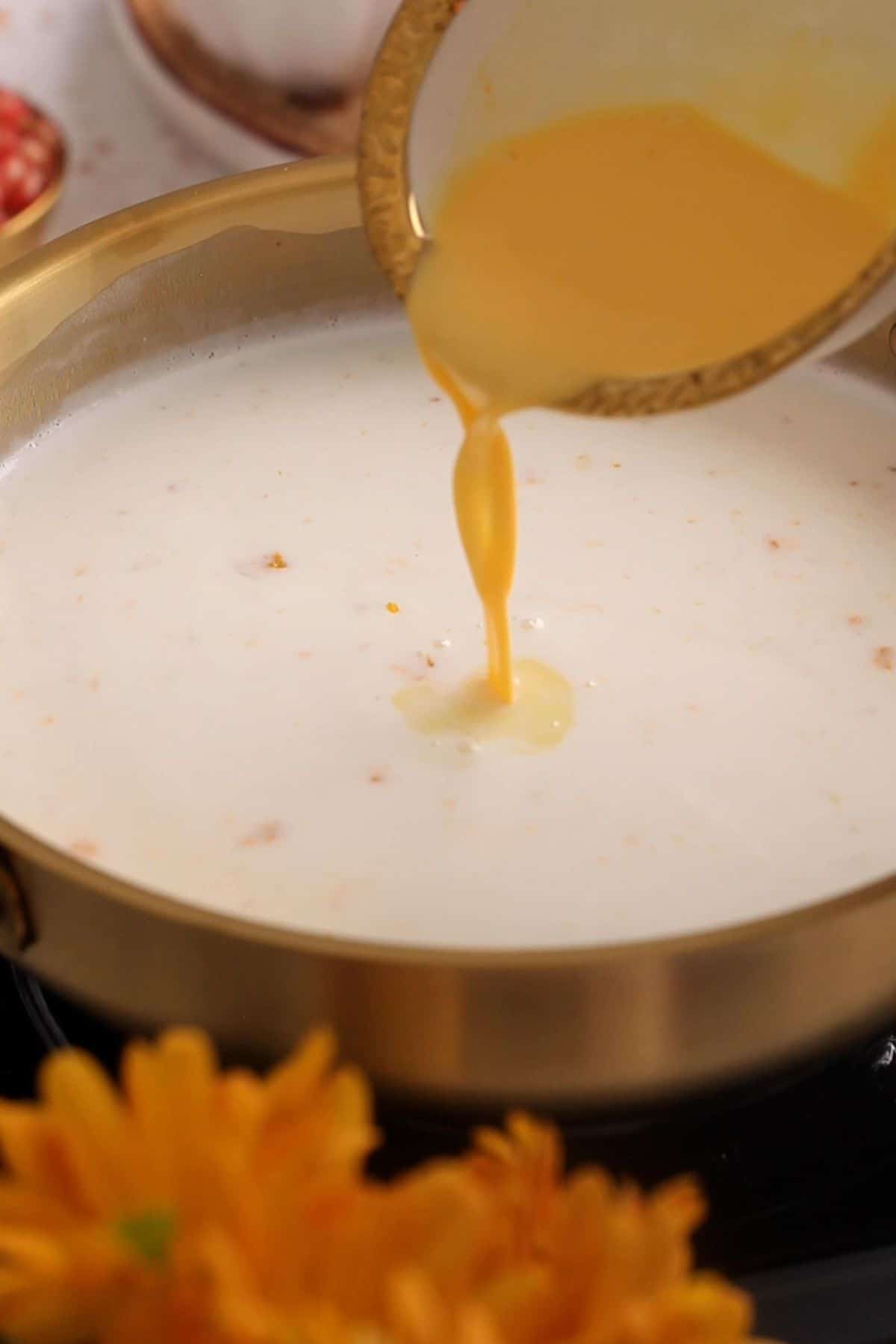 Custard powder slurry is added to simmering milk.
