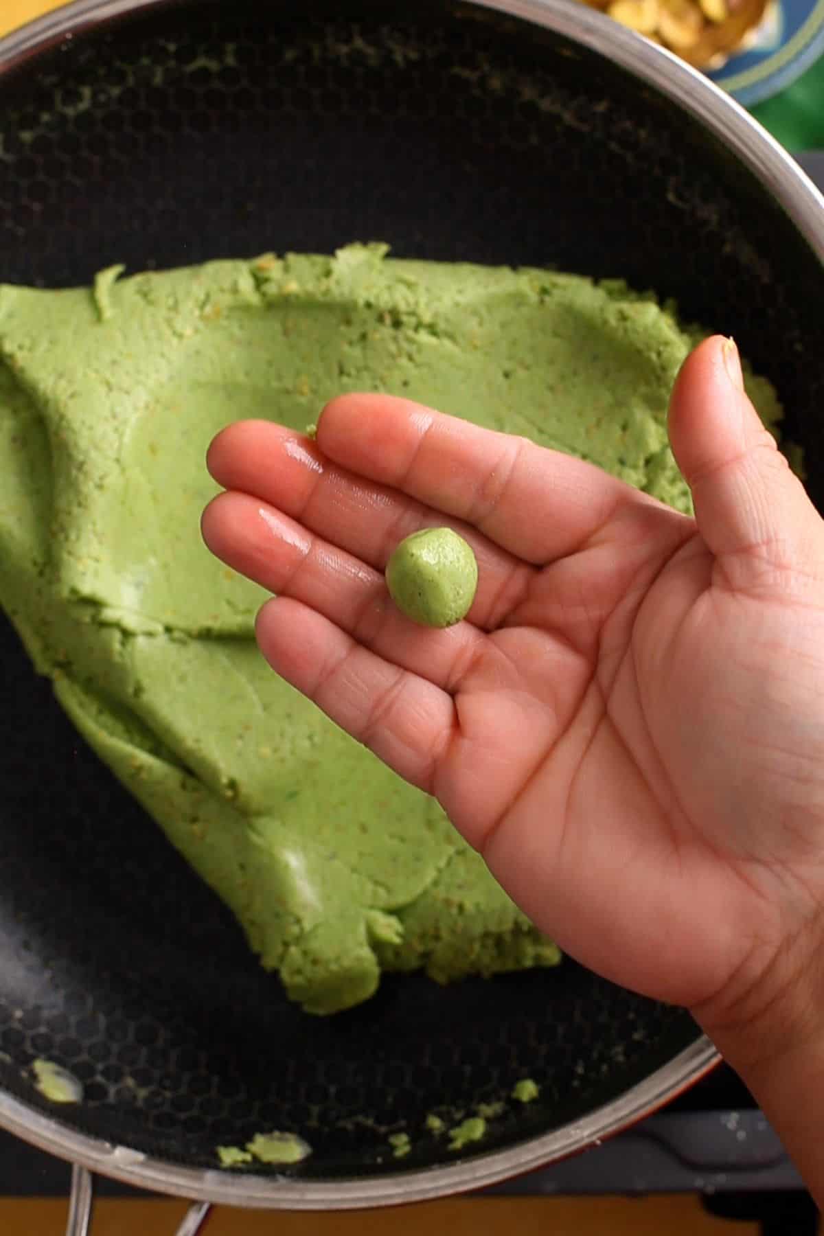 Checking the doneness of burfi mixture by making a ball.