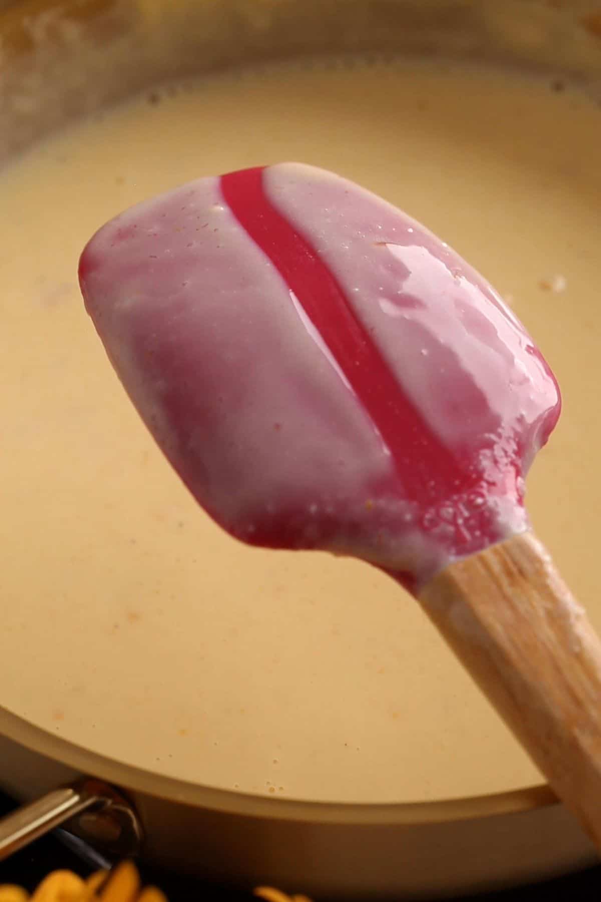 Checking custard consistency on back of red spatula.