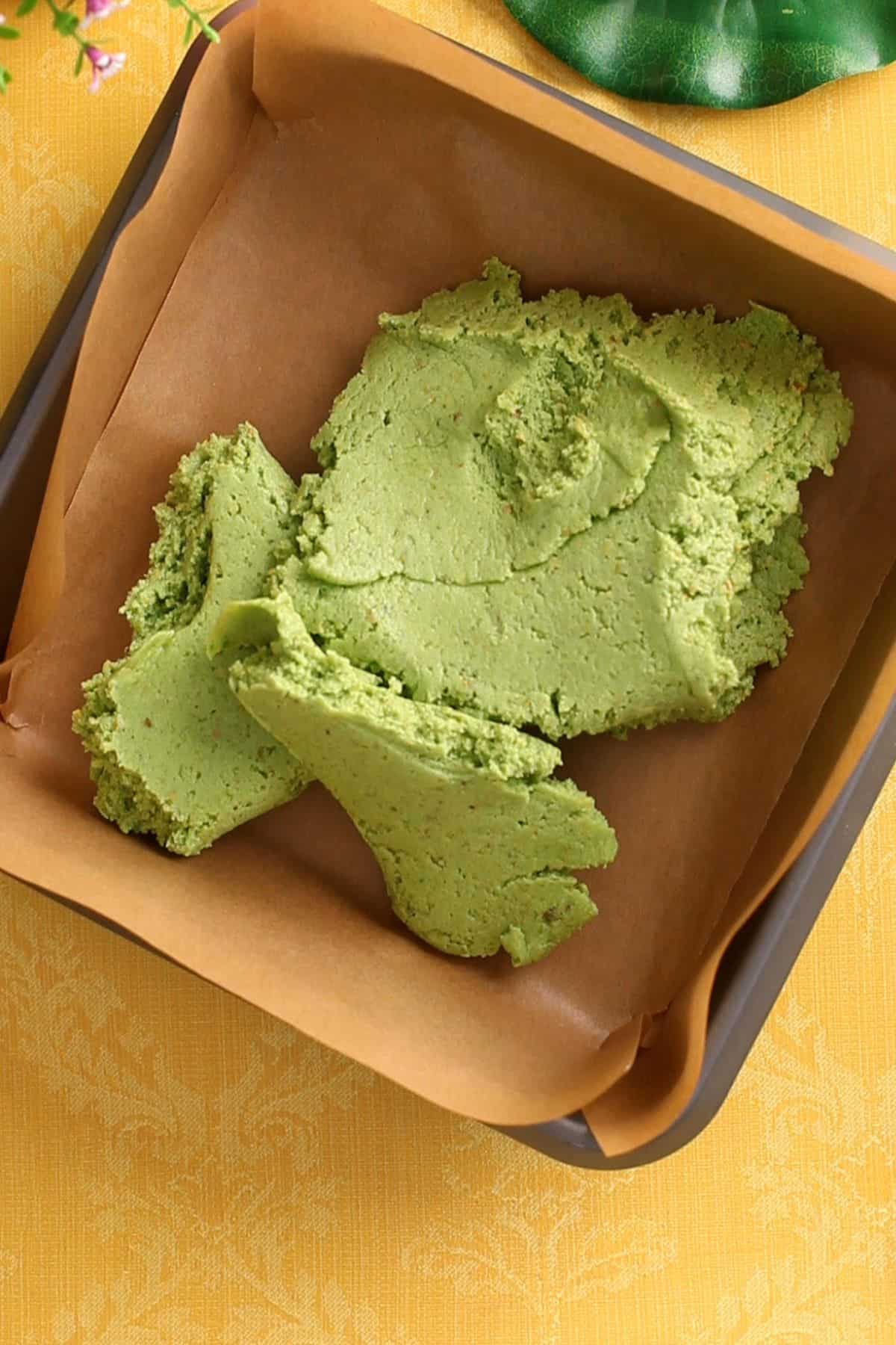 The burfi mixture is transferred to a lined square tray.