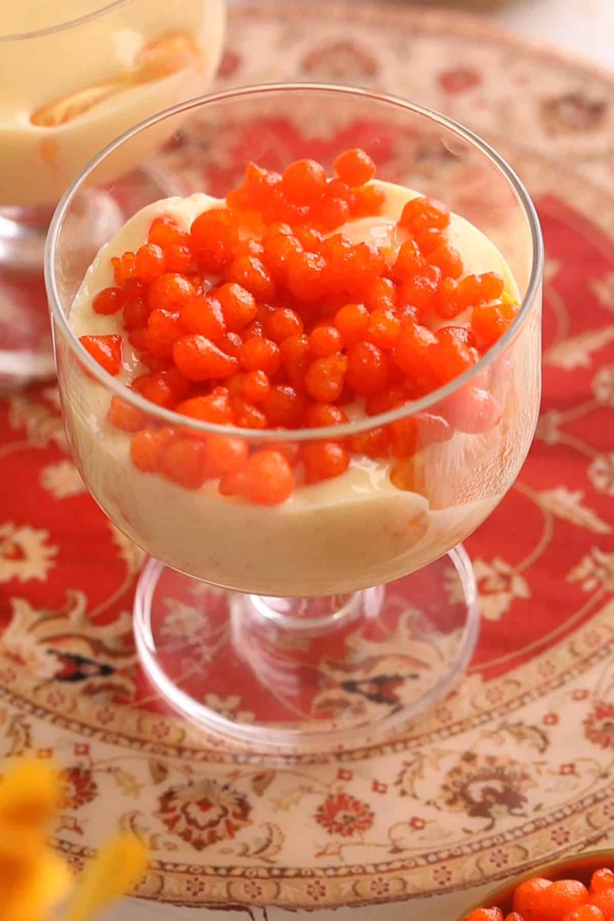 Sweet boondi is added on op of custard.