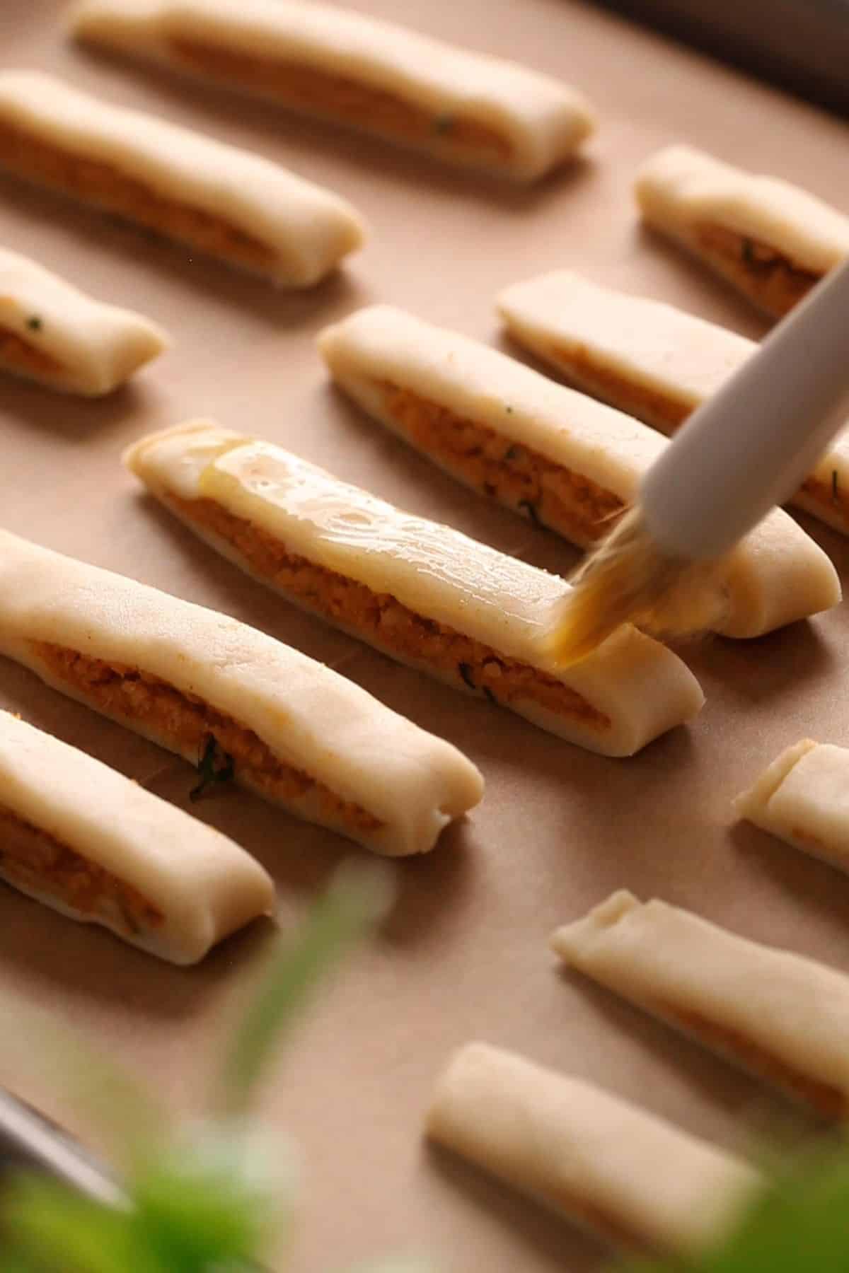 Butter is brushed on samosa sticks before baking.