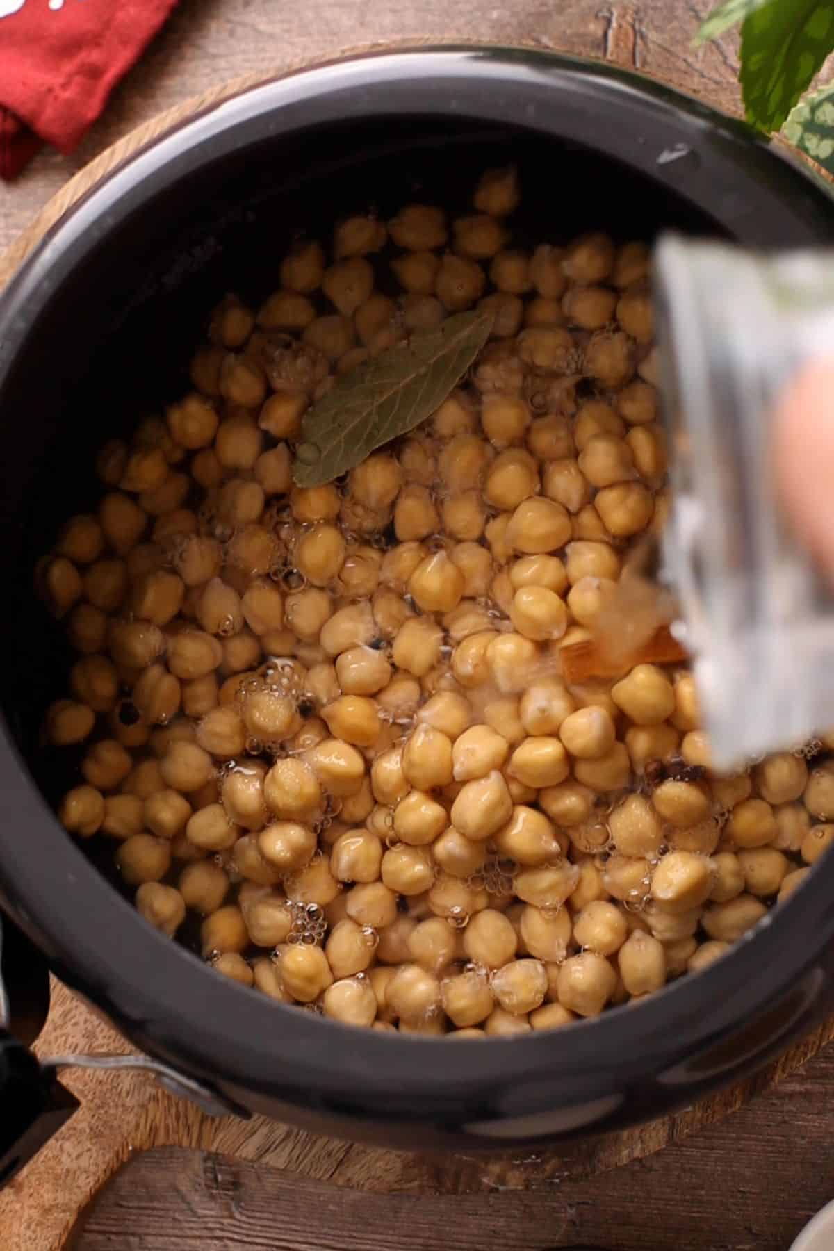 Adding water to the chickpeas to boil them.