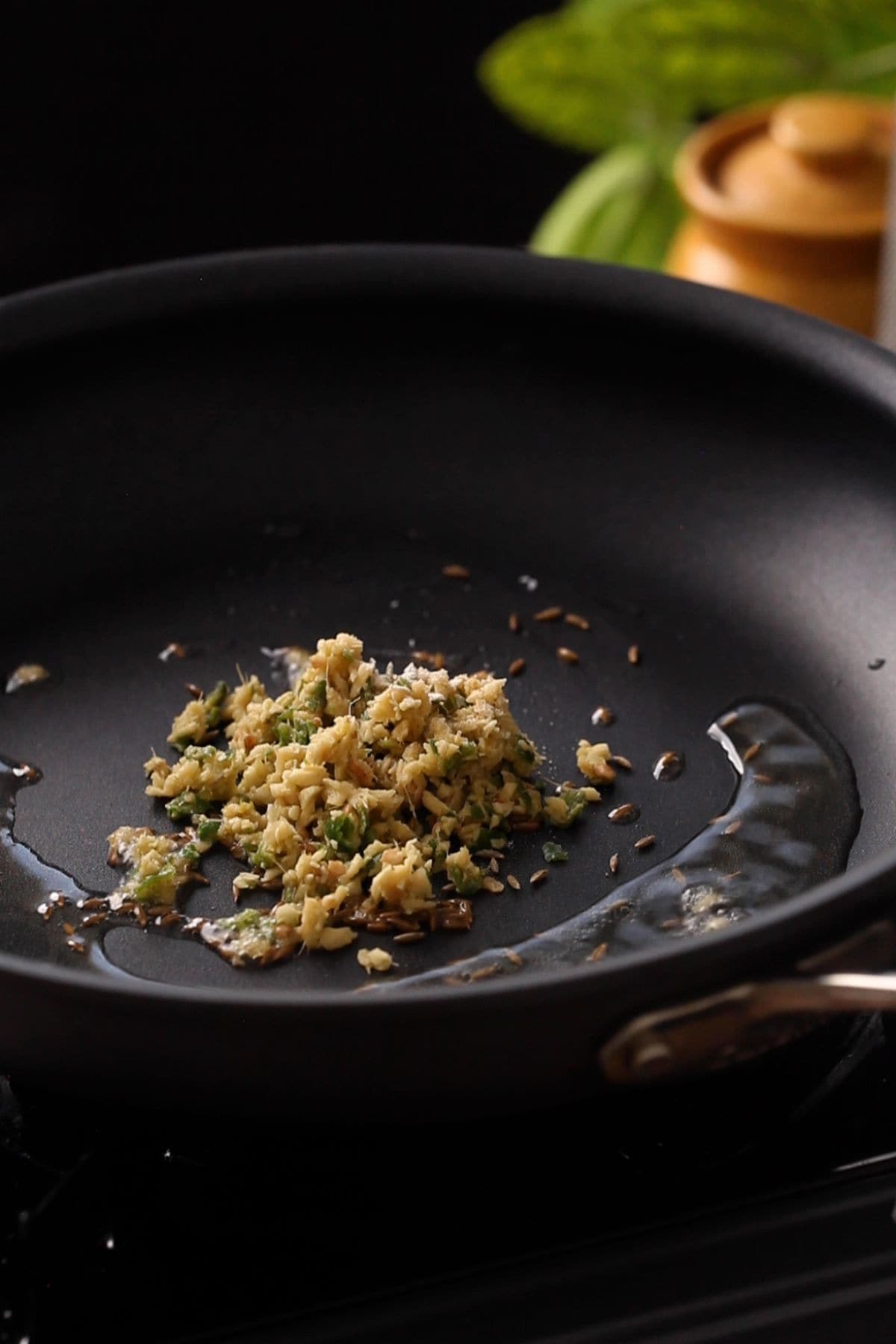 Minced ginger and garlic in hot oil in a black skillet.