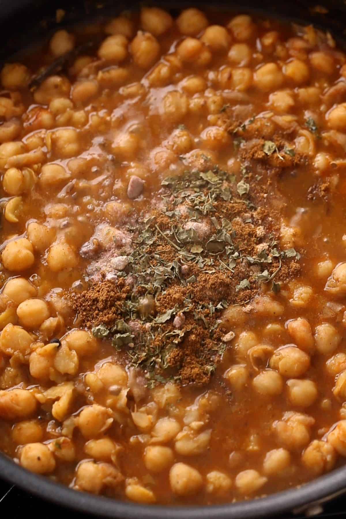 Chole for chaat are finished with spices and dried herbs.