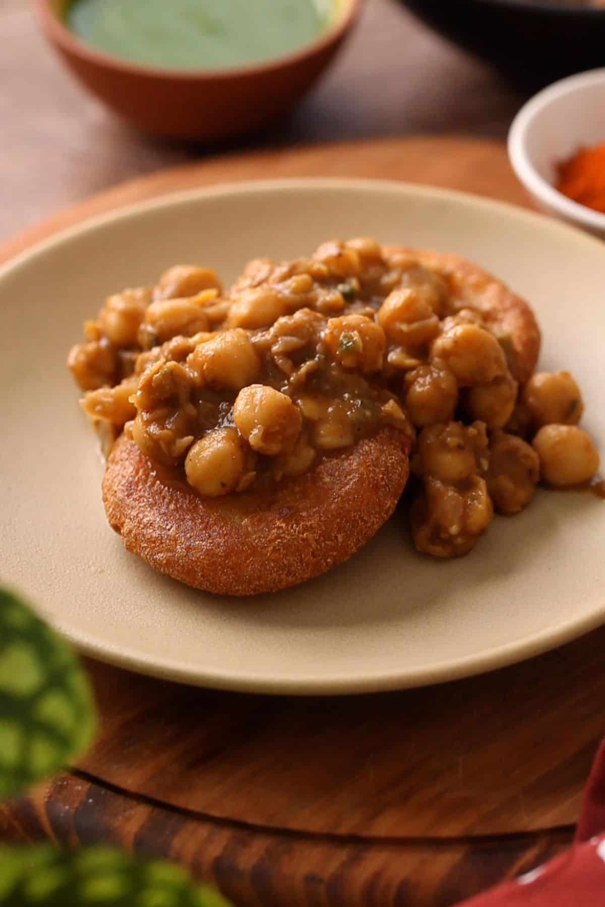 Chana curry is added over aloo tikki in a beige color plate.